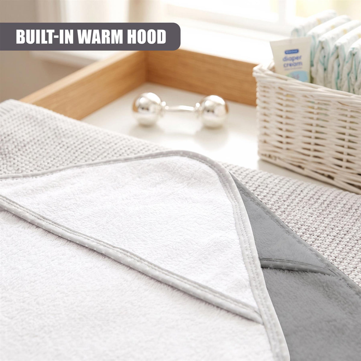 Grey hooded baby bath towel from GEEZY, part of a set of two, sits on a white tray with baby essentials