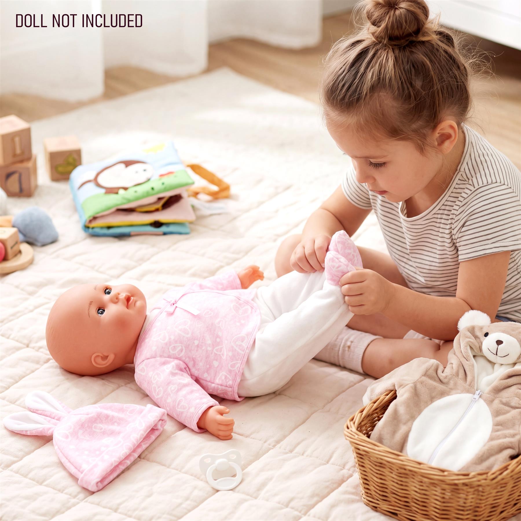 Doll wearing a pink outfit near a basket holding stuffed bear and corresponding clothes.