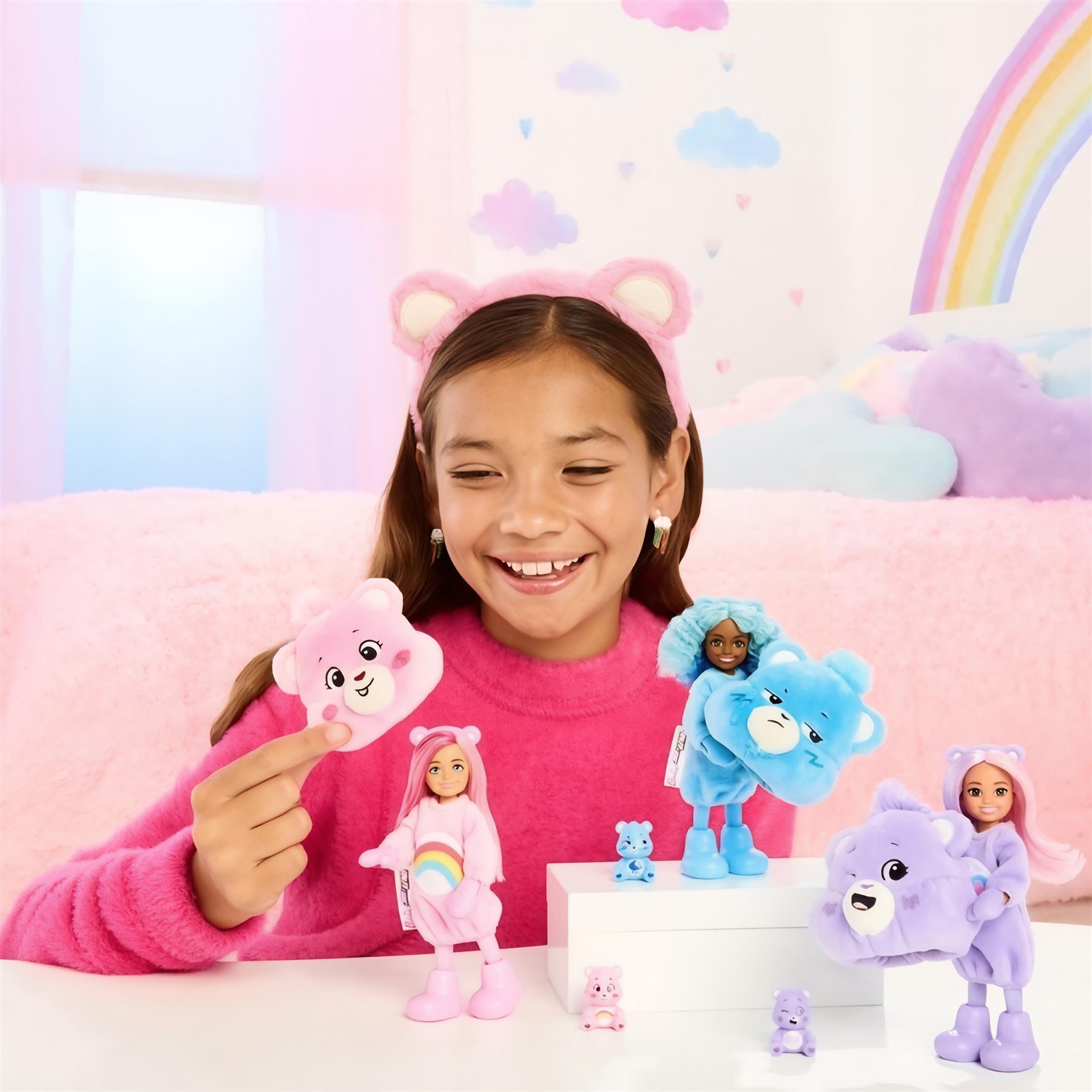 Young girl smiles, holding a plush pink Care Bear next to several blue, purple, and doll toys.