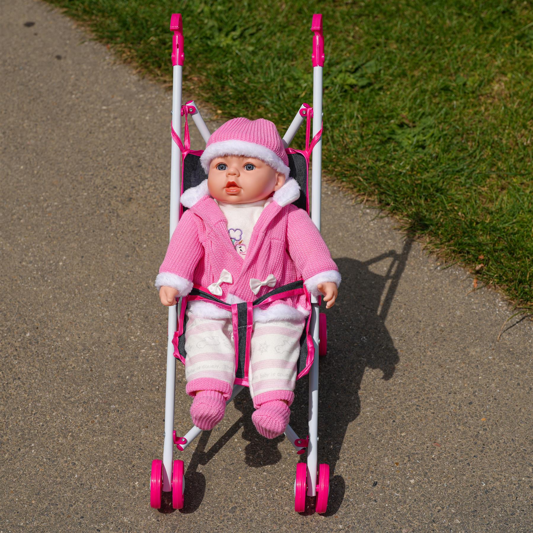 This is a pink foldable stroller, suitable for baby dolls. It's designed for easy storage and transportation. The stroller has a sleek design, with a smooth finish, and it's currently displayed in a shop called 'themagictoyshop'.