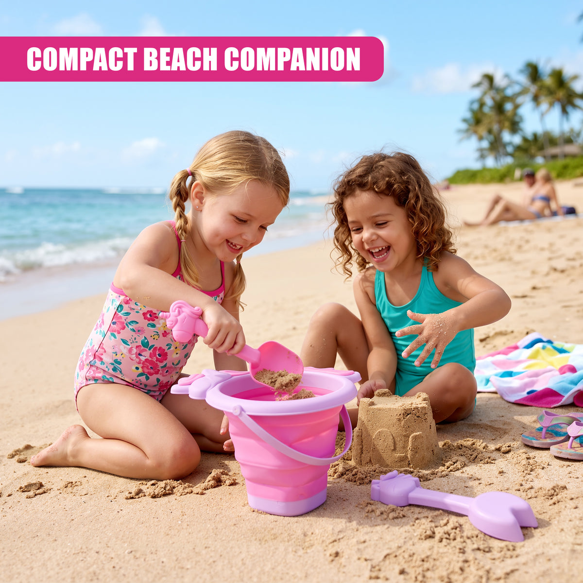 Two young girls play with a pink collapsible bucket and spade on a sandy beach