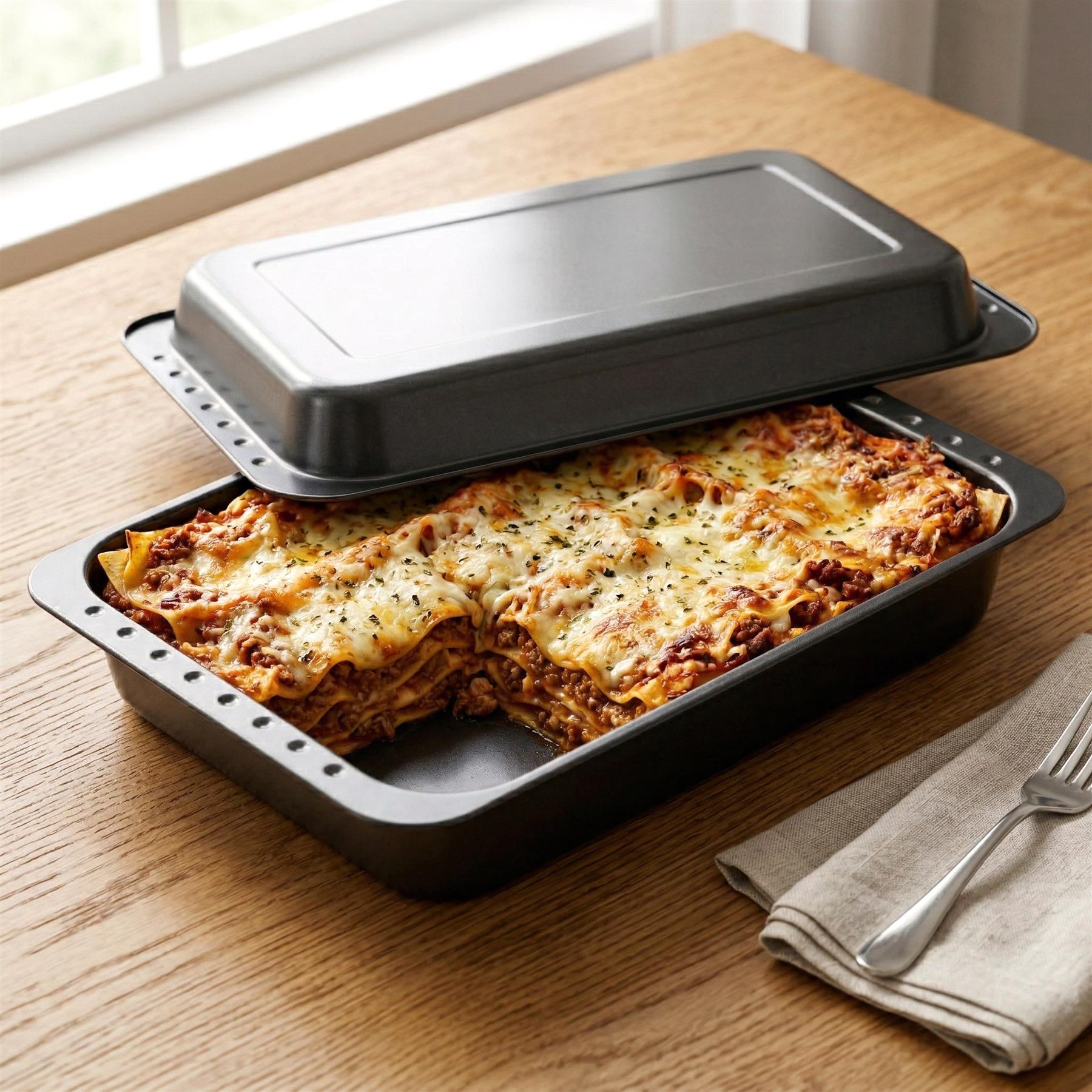 Baked gratin in the lower roasting tin, covered by a lid, set on a wooden counter with utensils.