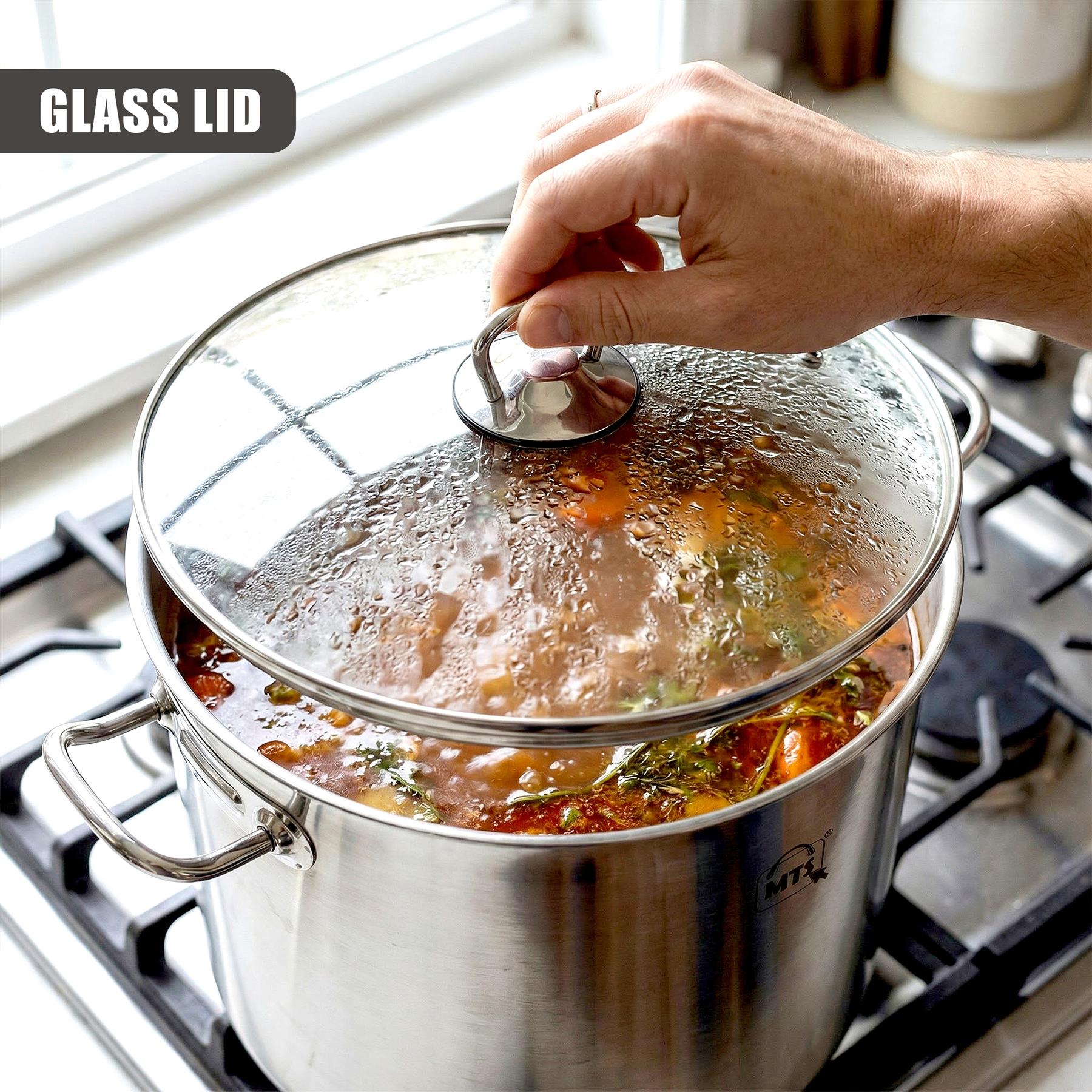 A hand adjusts the glass lid on a stainless steel stockpot simmering liquid on a stove.