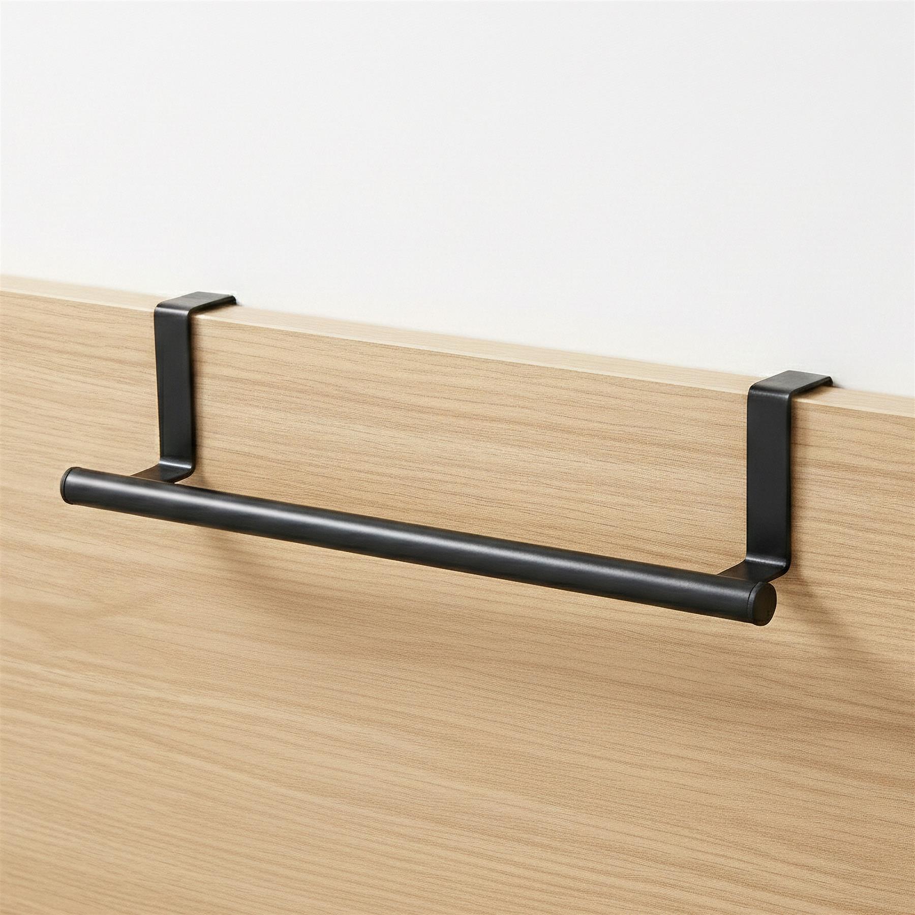 A black metal rail is mounted horizontally on a light wood grain surface.