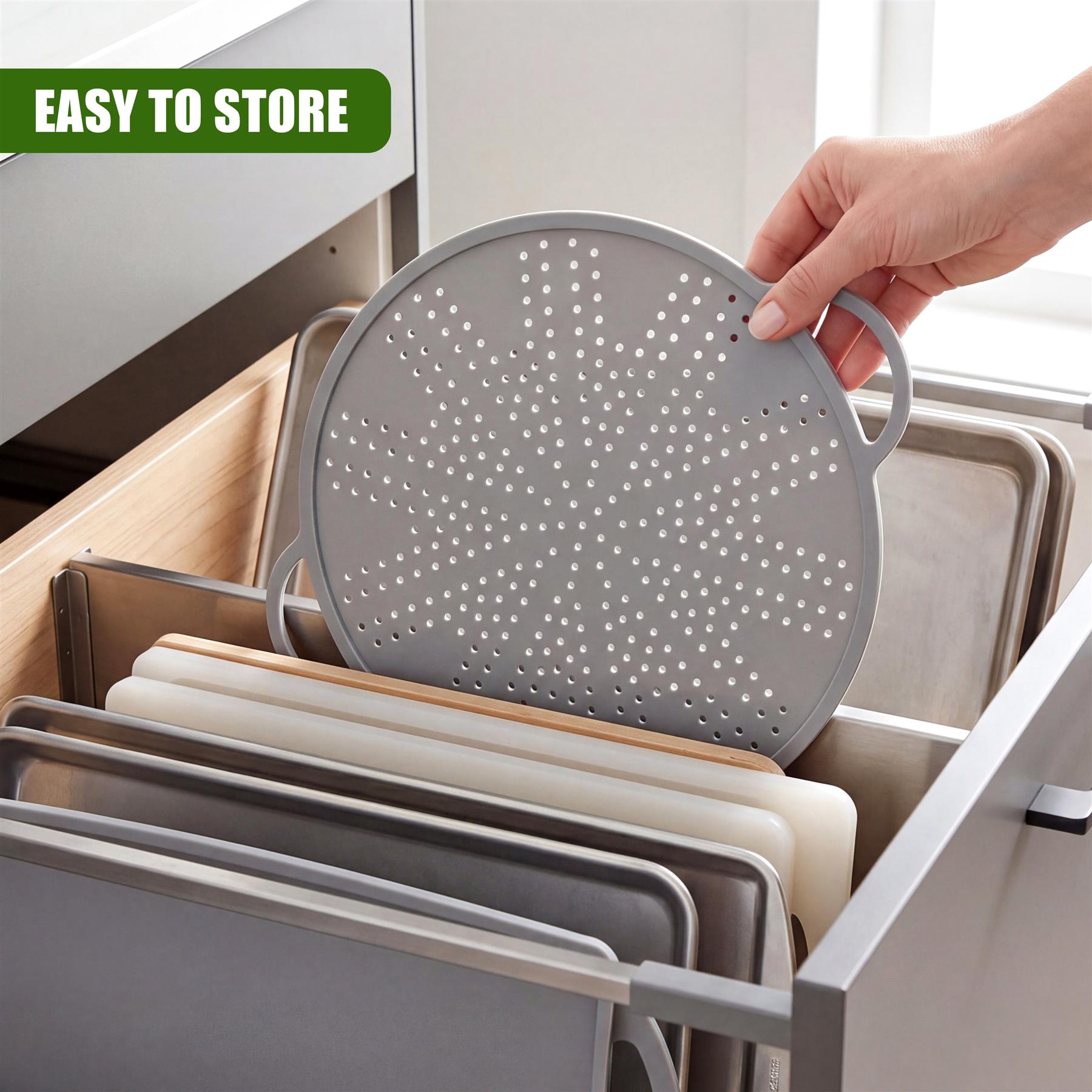 Hand holding a round, perforated gray silicone strainer placed among storage organizers inside a drawer.