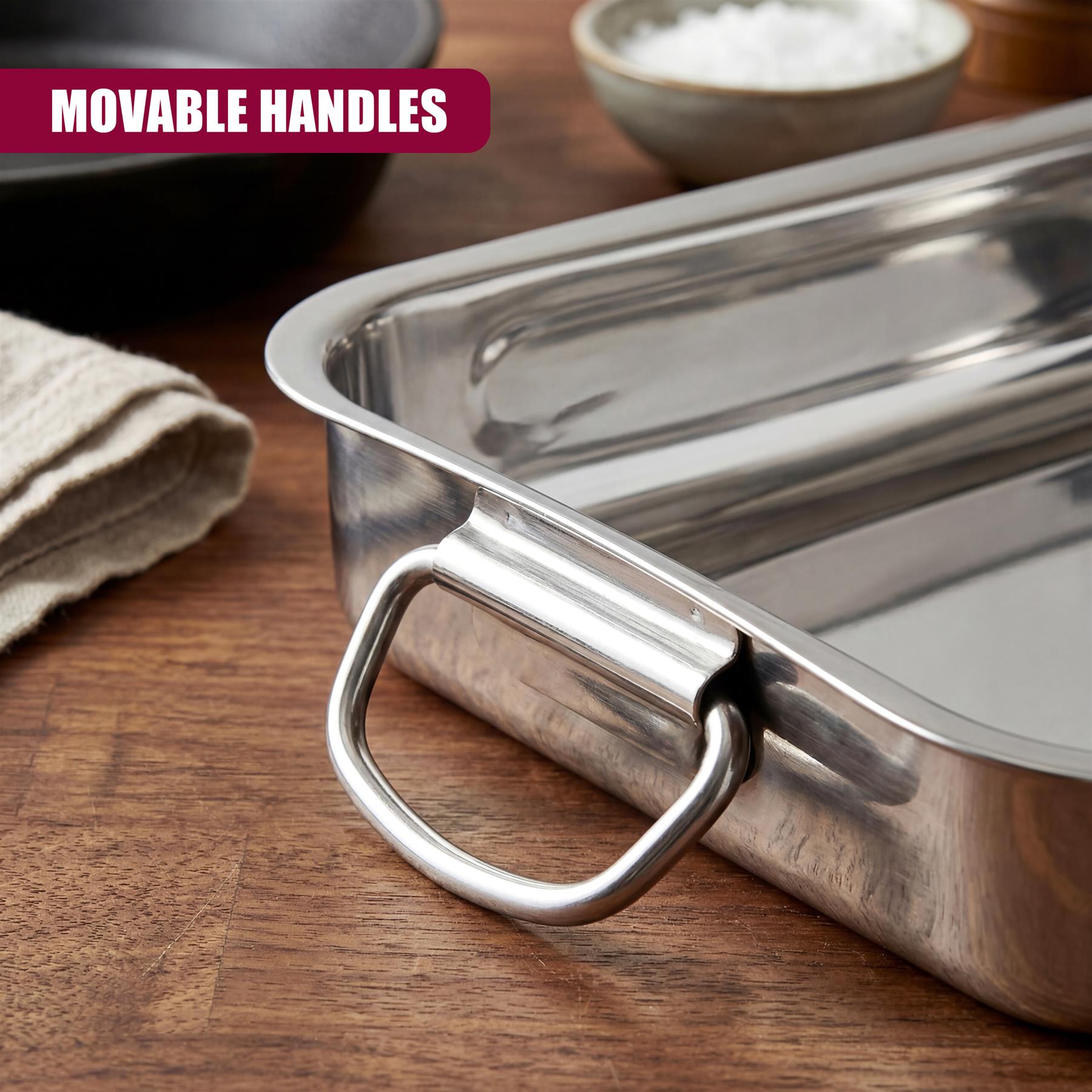 Stainless steel roasting tray featuring an attached handle, displayed on a dark wooden kitchen surface.