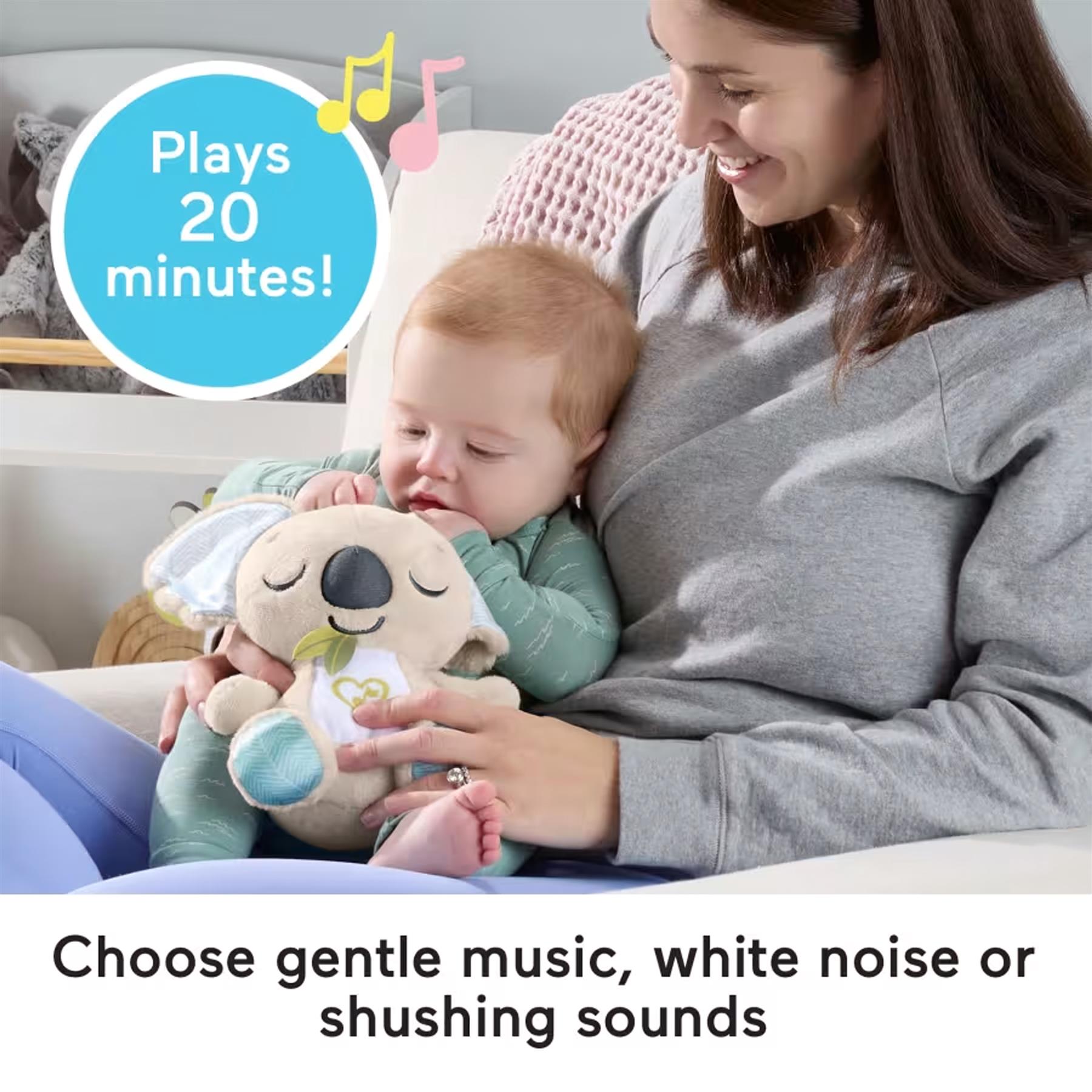 A woman sits with an infant who is interacting with a soft, stuffed koala toy.