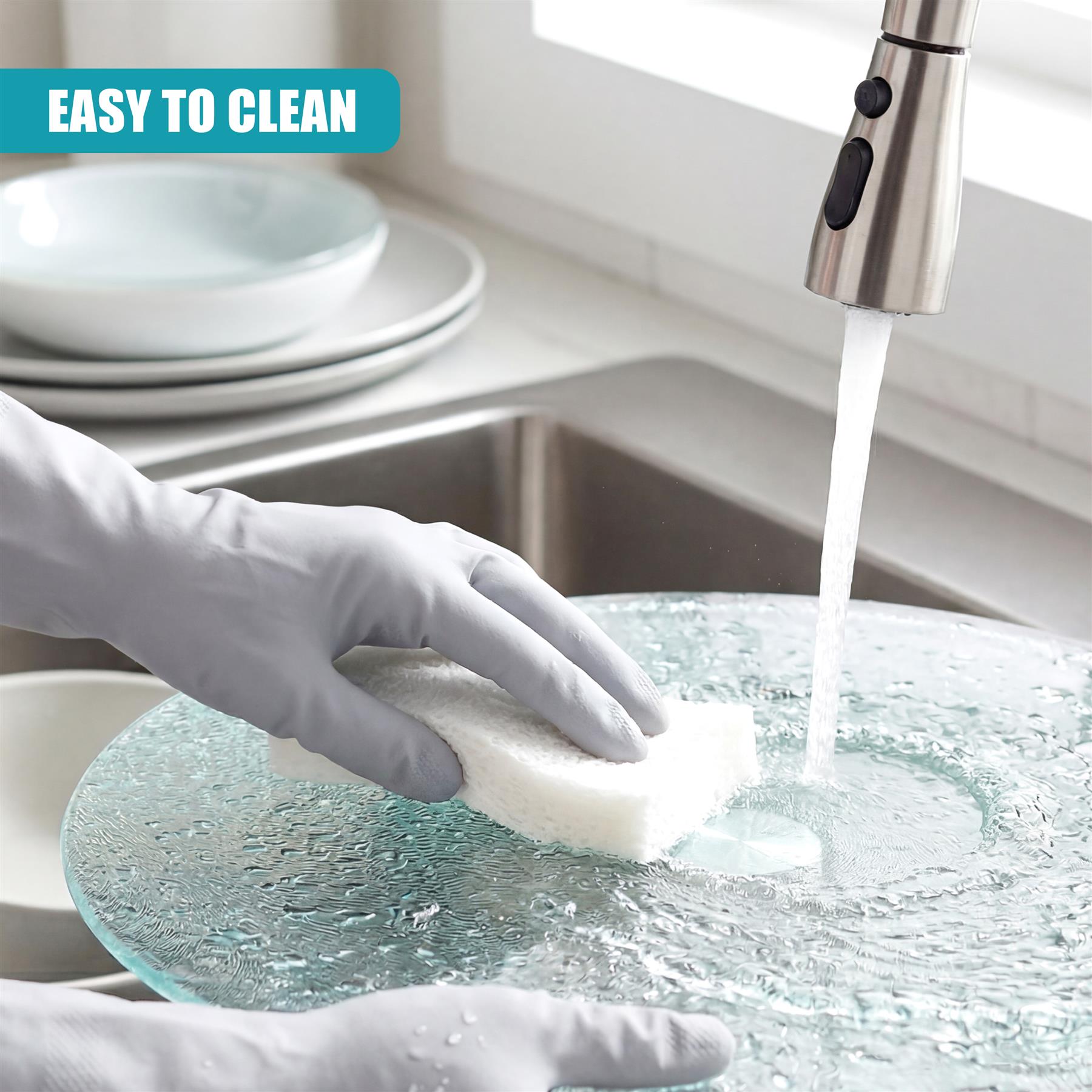 A gloved hand cleans a glass cake stand under running water from a kitchen faucet.