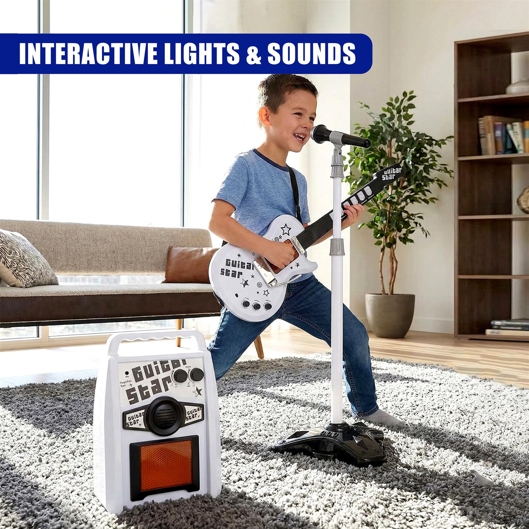 A young boy plays a white electric guitar into a microphone next to a speaker amplifier unit.