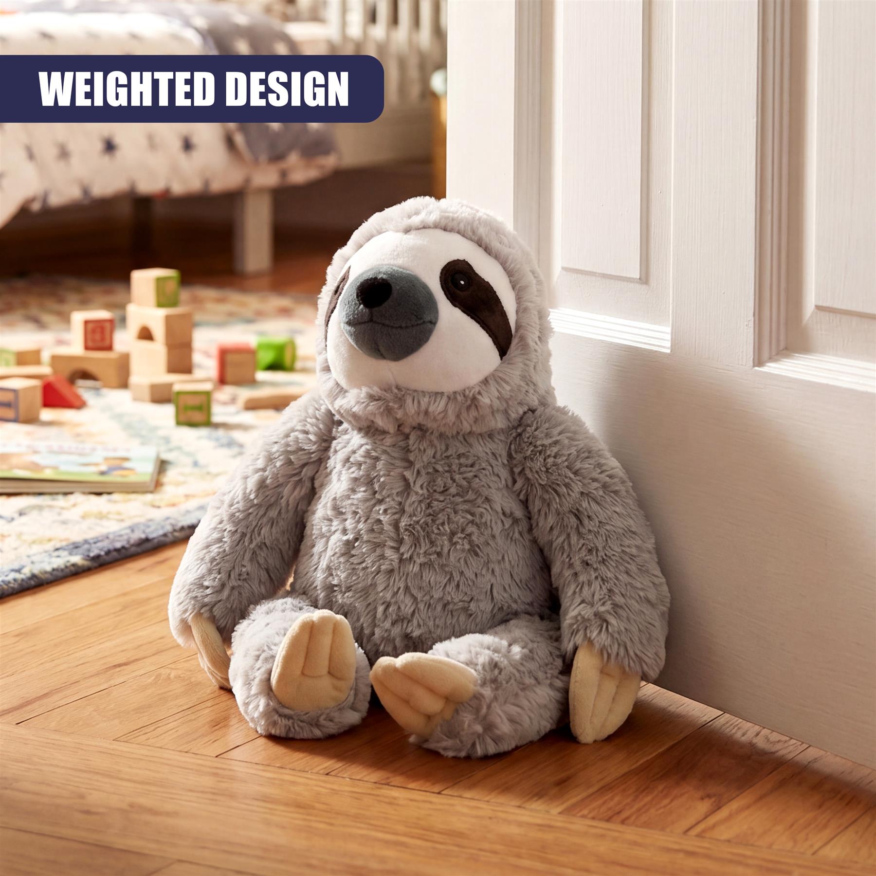 Plush gray sloth figure sitting on a hardwood floor next to a white door jamb.