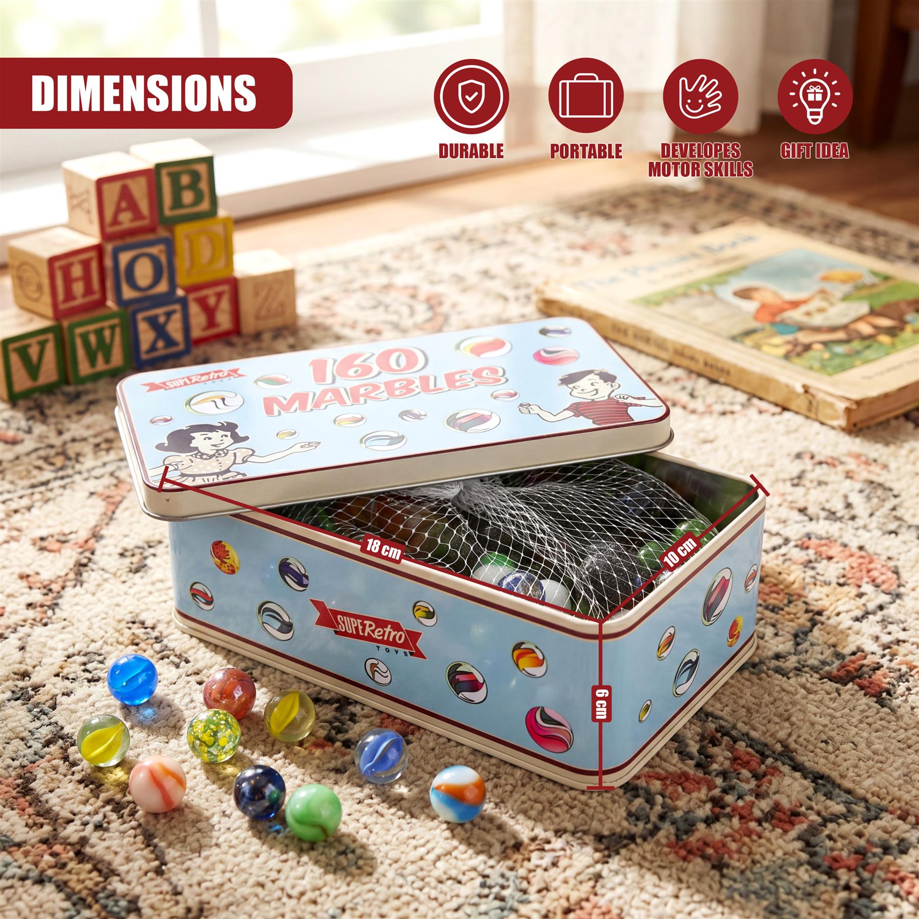 A hinged tin box filled with marbles rests on a surface next to alphabet blocks.