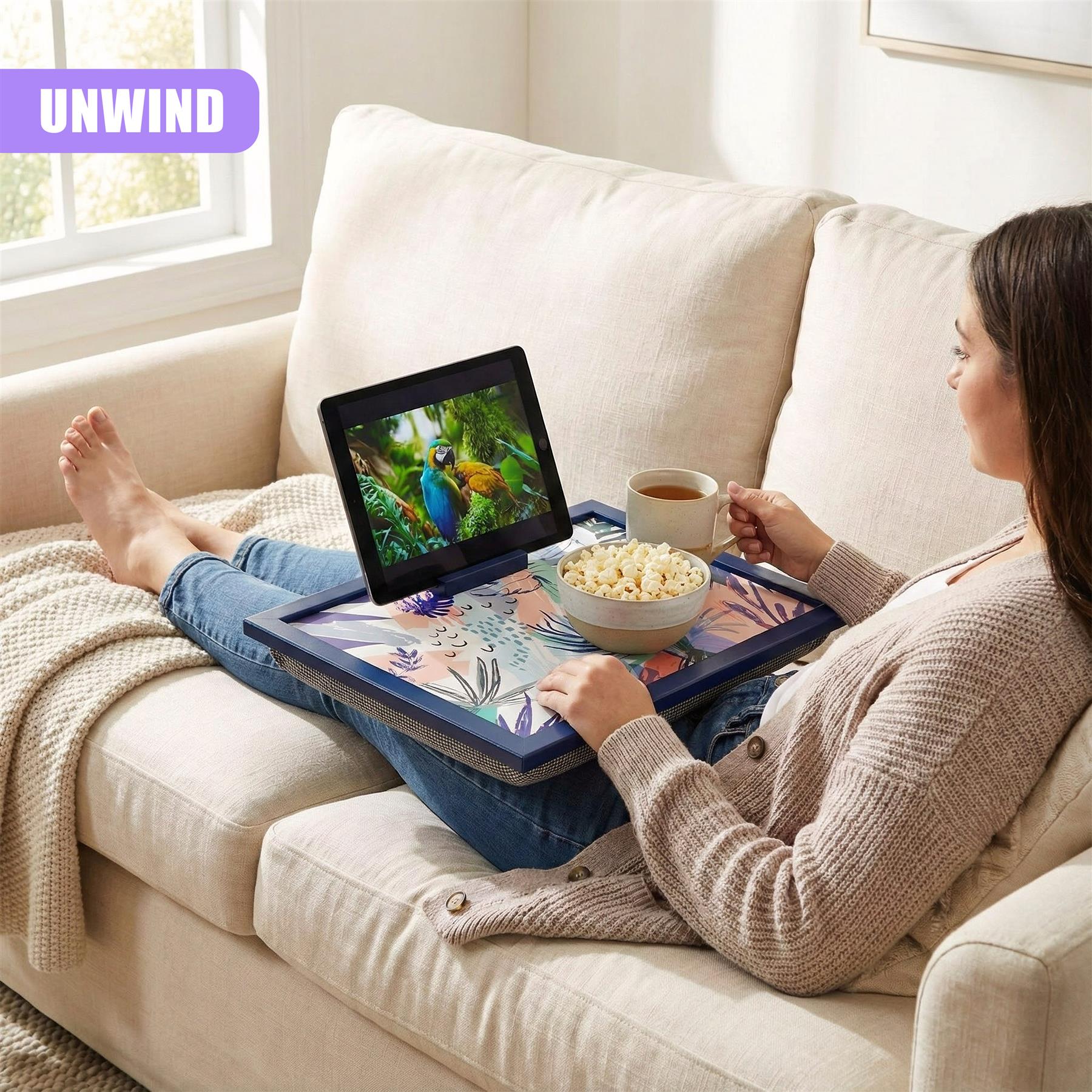 Woman using lap tray with cushion while relaxing on a sofa.