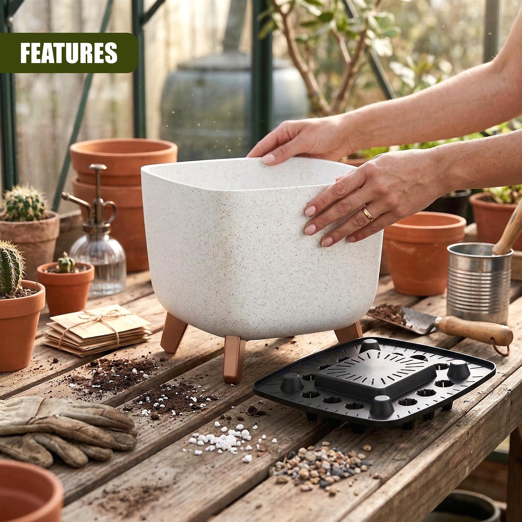 Hands hold a light-colored potted plant resting near a black square drainage tile on a rustic wooden table.
