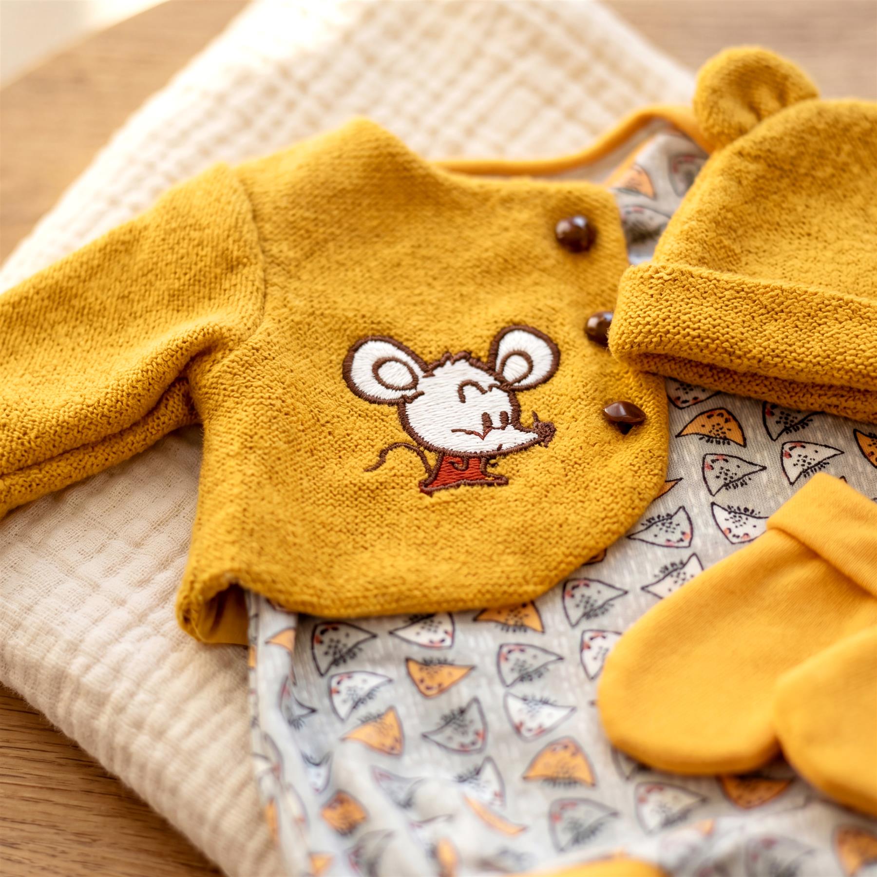 Mustard yellow knitted set featuring a mouse design, including a sweater, hat, and pair of mittens.