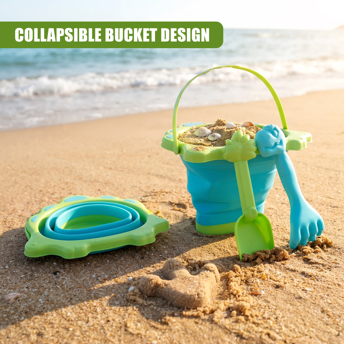 A blue and green collapsible beach bucket and spade set sits on sand, alongside a footprint, at a beach