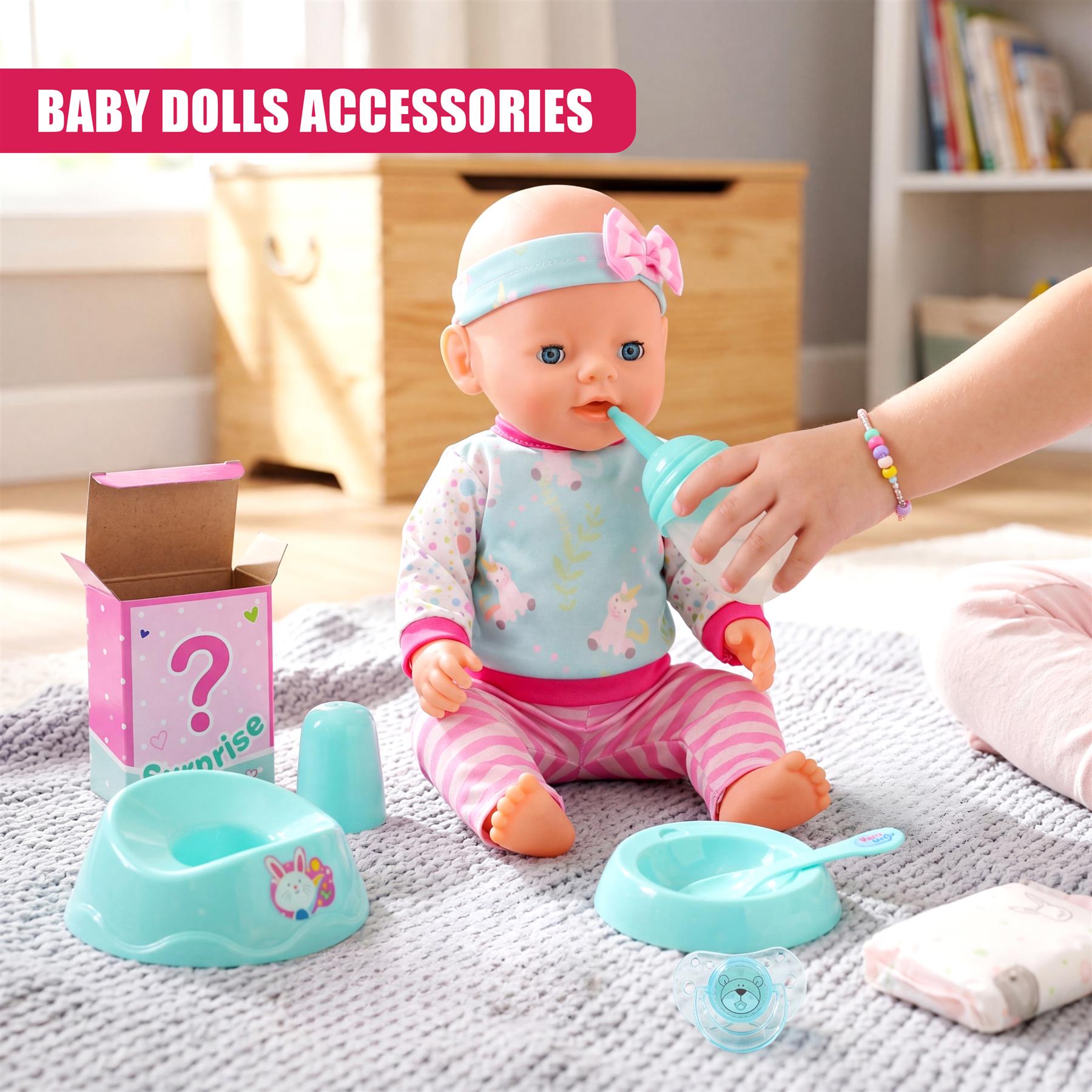 The baby doll sits surrounded by toys, receiving liquid from an adult's hand.