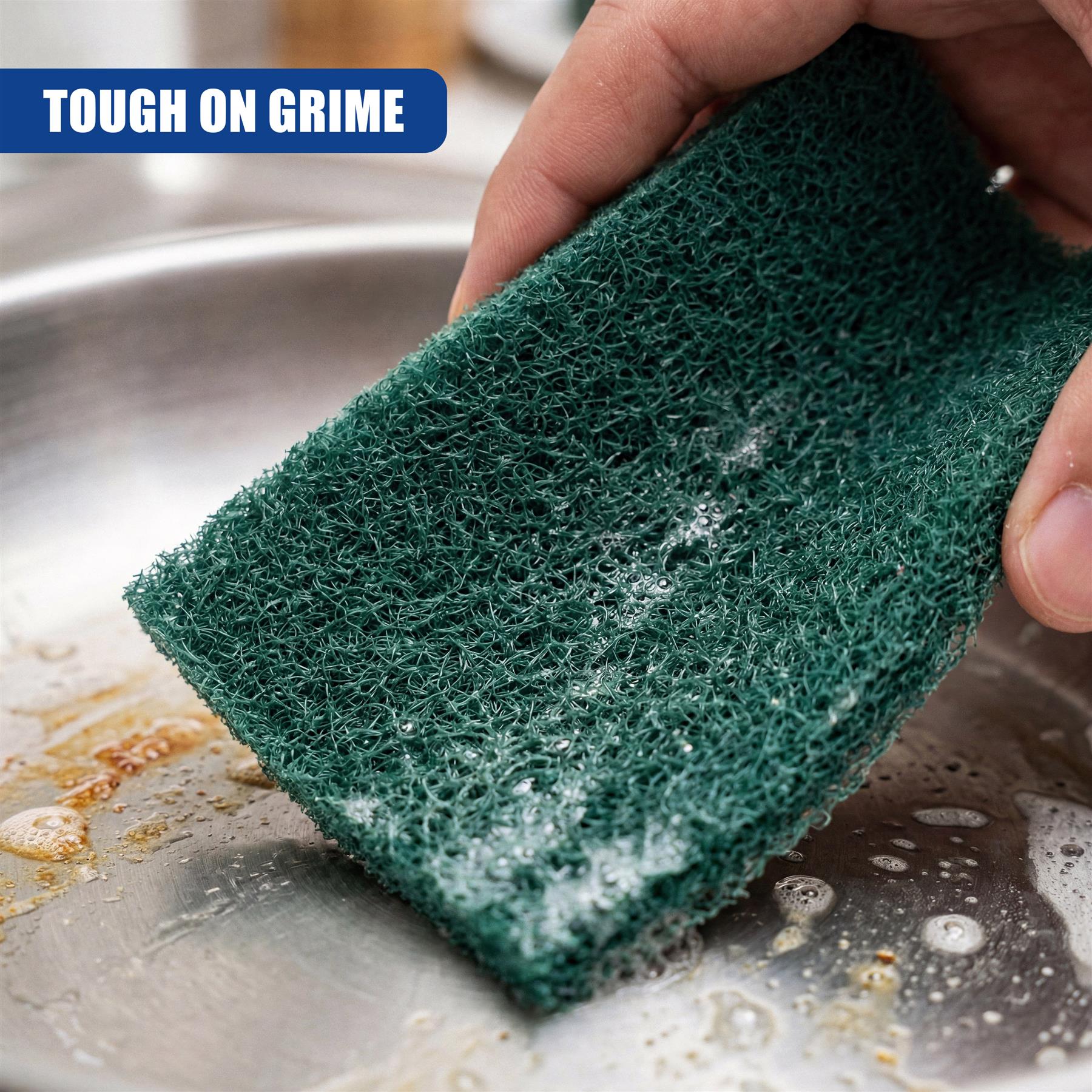 Hands hold a dark green scouring pad filled with soap residue over a dirty metal sink basin.