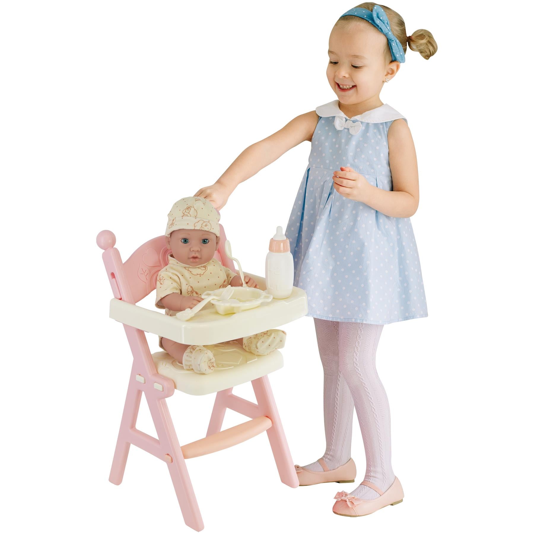 Baby doll with feeding high chair and accessories in hand. Little girl holding the doll. Polka dots on the girl's dress. - The Magic Toy Shop