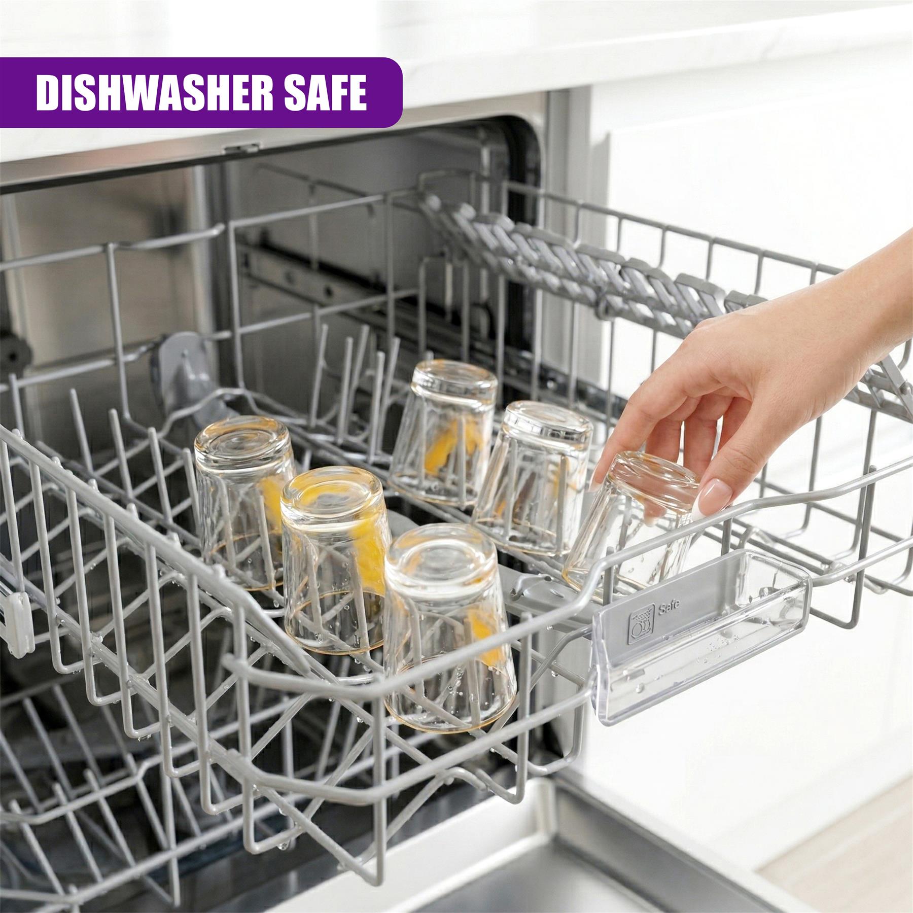 Mini glass shot glasses are placed inside a dishwasher rack, partially held by a person's hand.