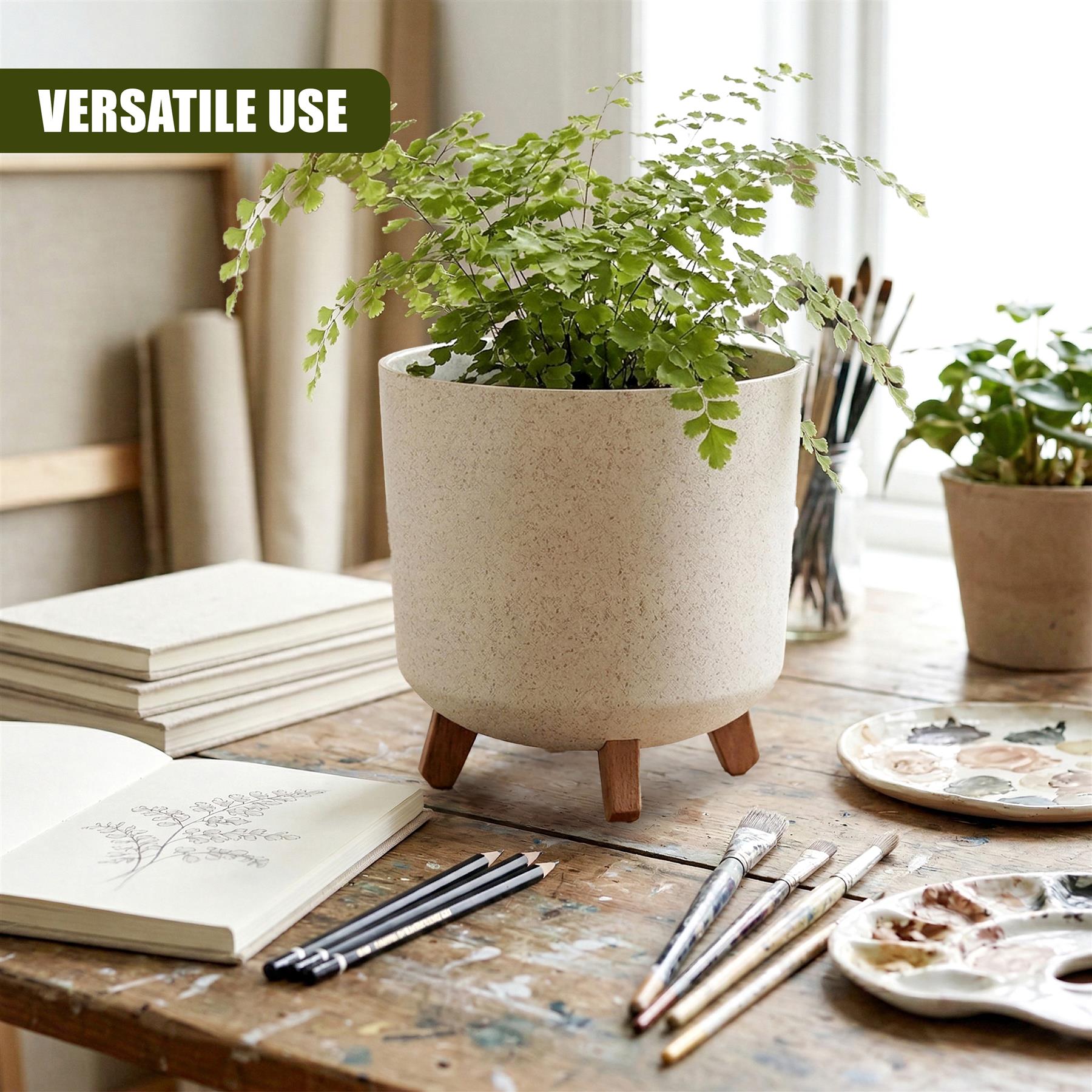 Beige potted plant with wooden legs rests on a rustic wooden table alongside tools and ceramic palettes.