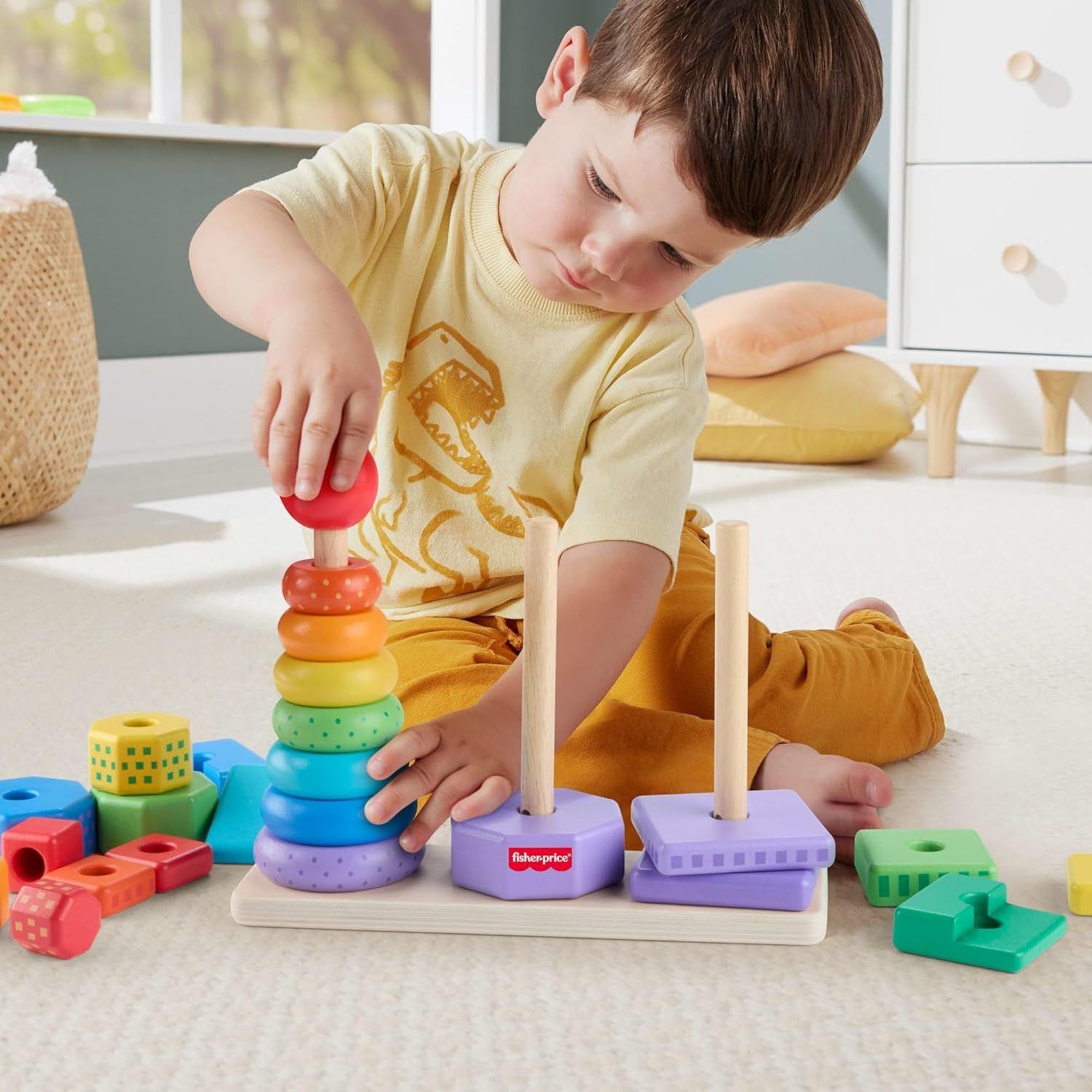 A boy stacks colorful wooden rings on a base unit next to a shape sorting activity toy.