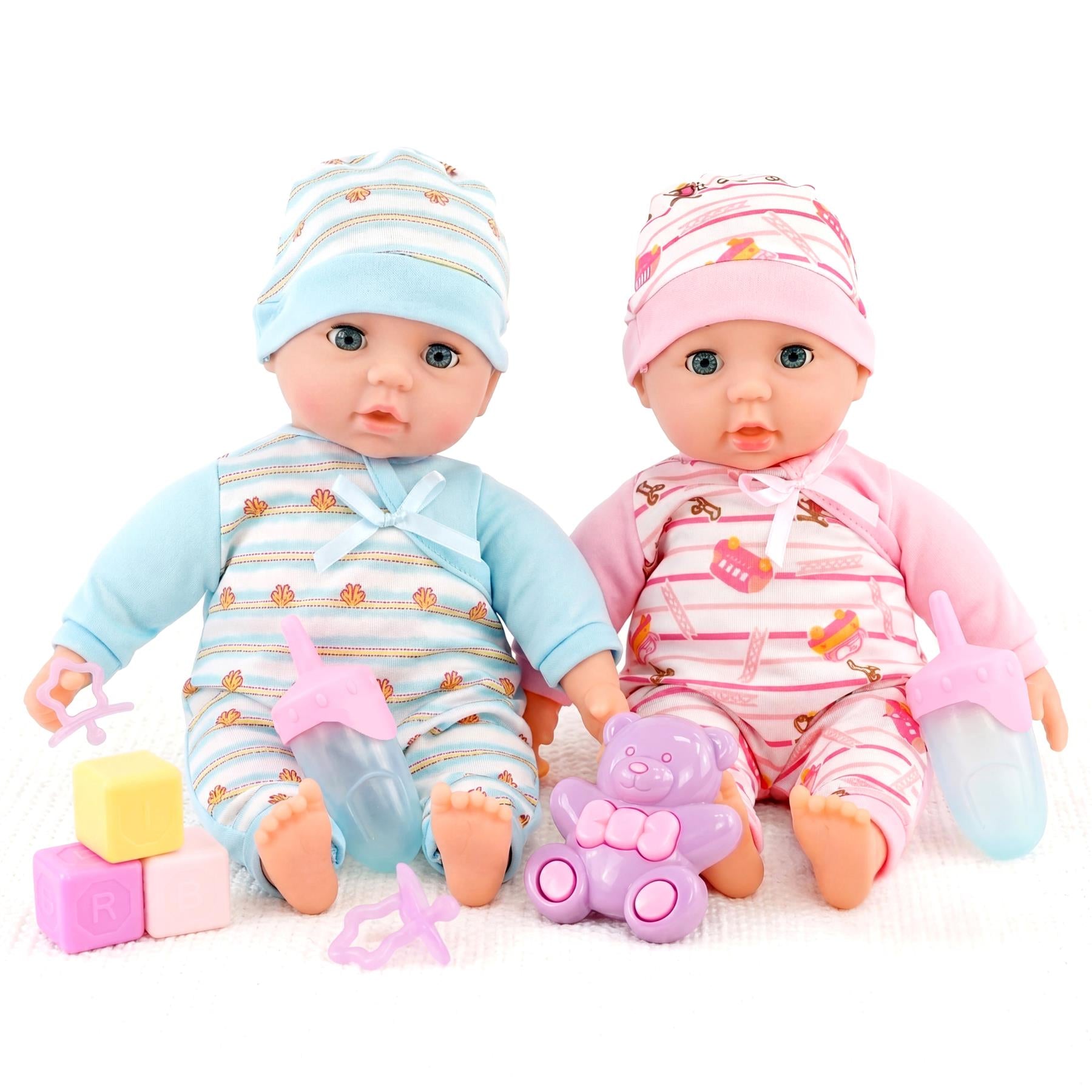 Two baby dolls in striped outfits sit among colorful blocks, bottles, and plush toy accessories.