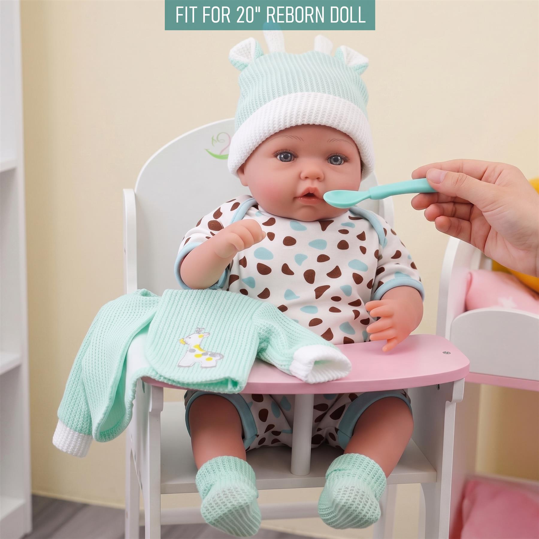 A doll is seated, wearing a spotted outfit, with a mint jacket resting on the chair.