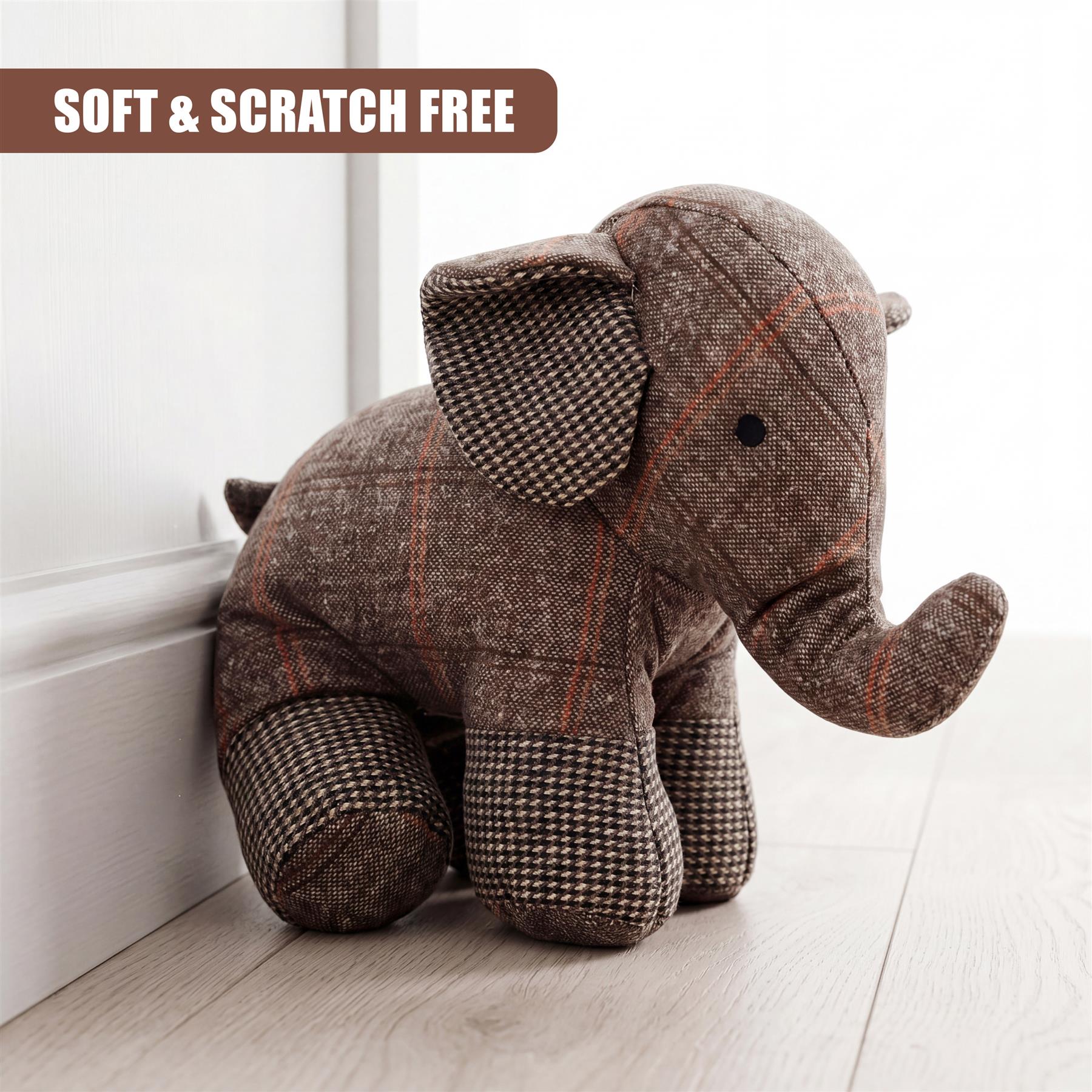 A plaid elephant figure sits leaning against a white door frame on a wooden floor.