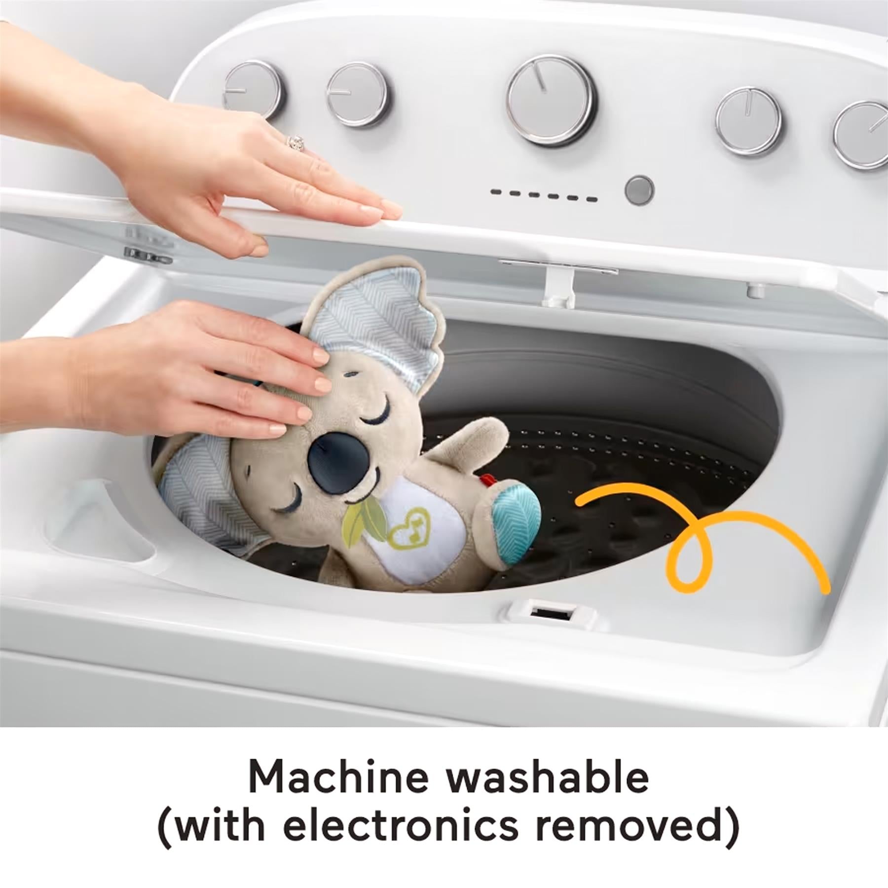 A koala soother toy sits inside the open drum of a washing machine.