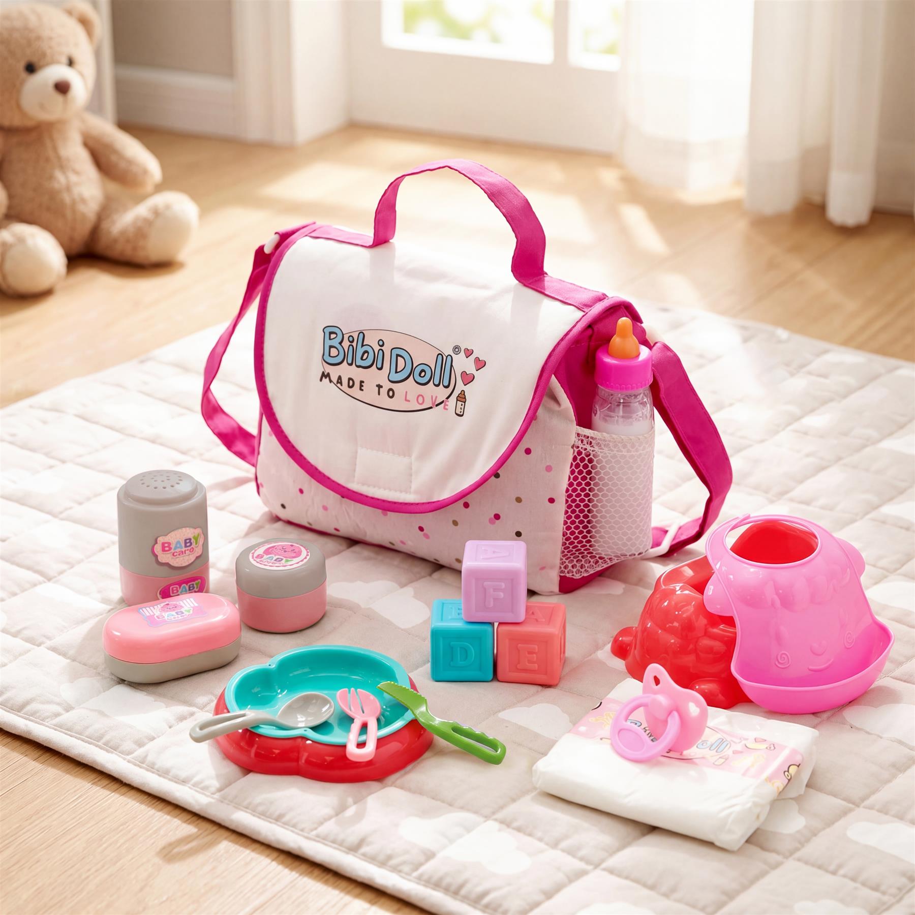 A pink changing bag sits on a mat with baby toys, accessories, and washcloths.