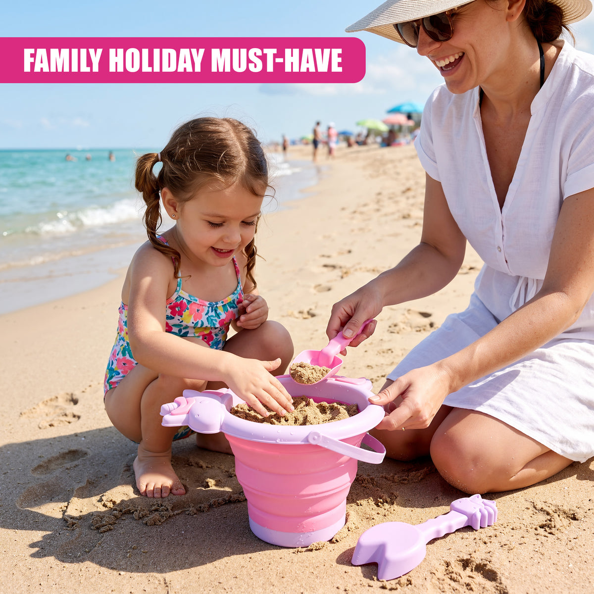 A mother and daughter play on a beach with pink collapsible buckets and spades