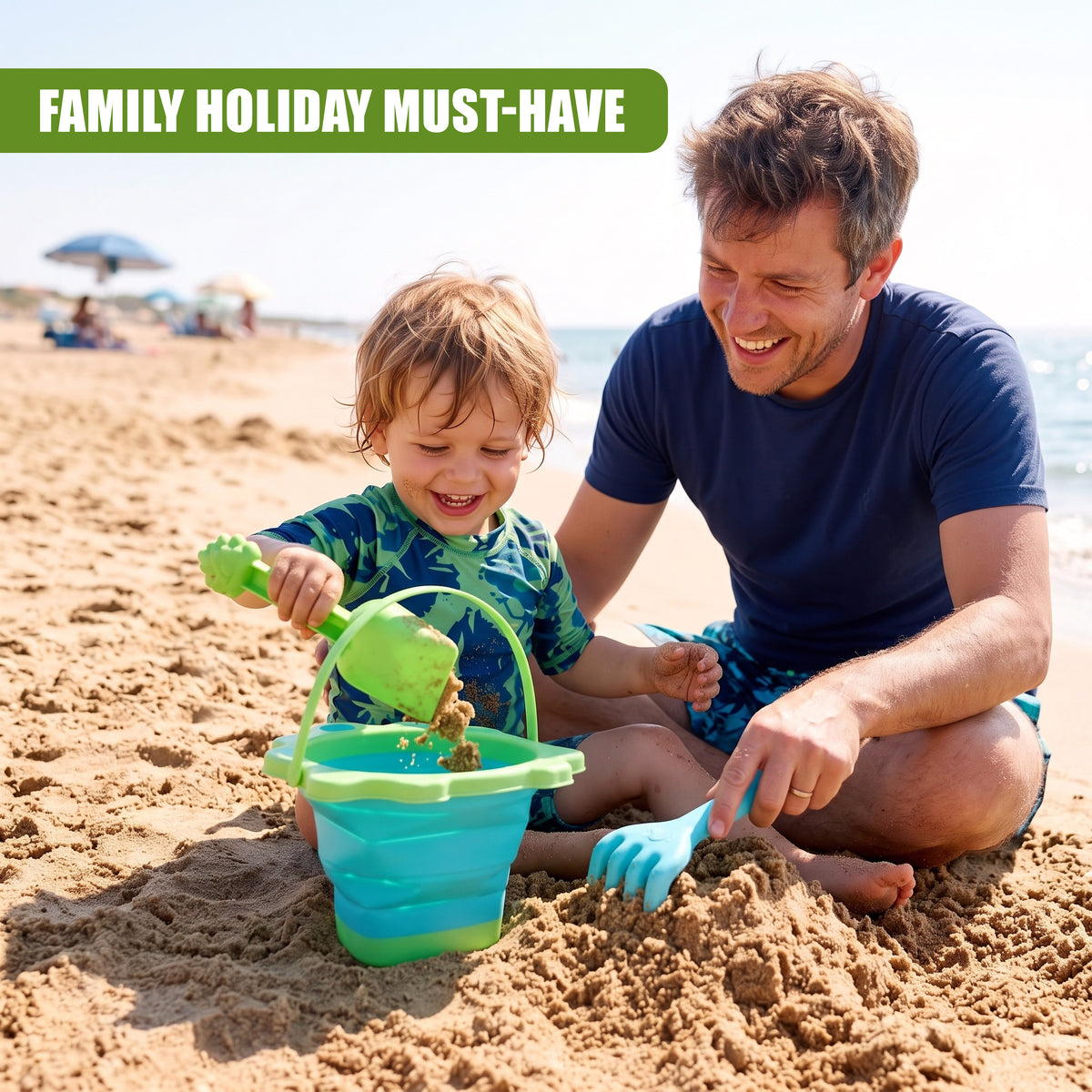 A father and young child play on a beach with a green and blue collapsible bucket and spade set