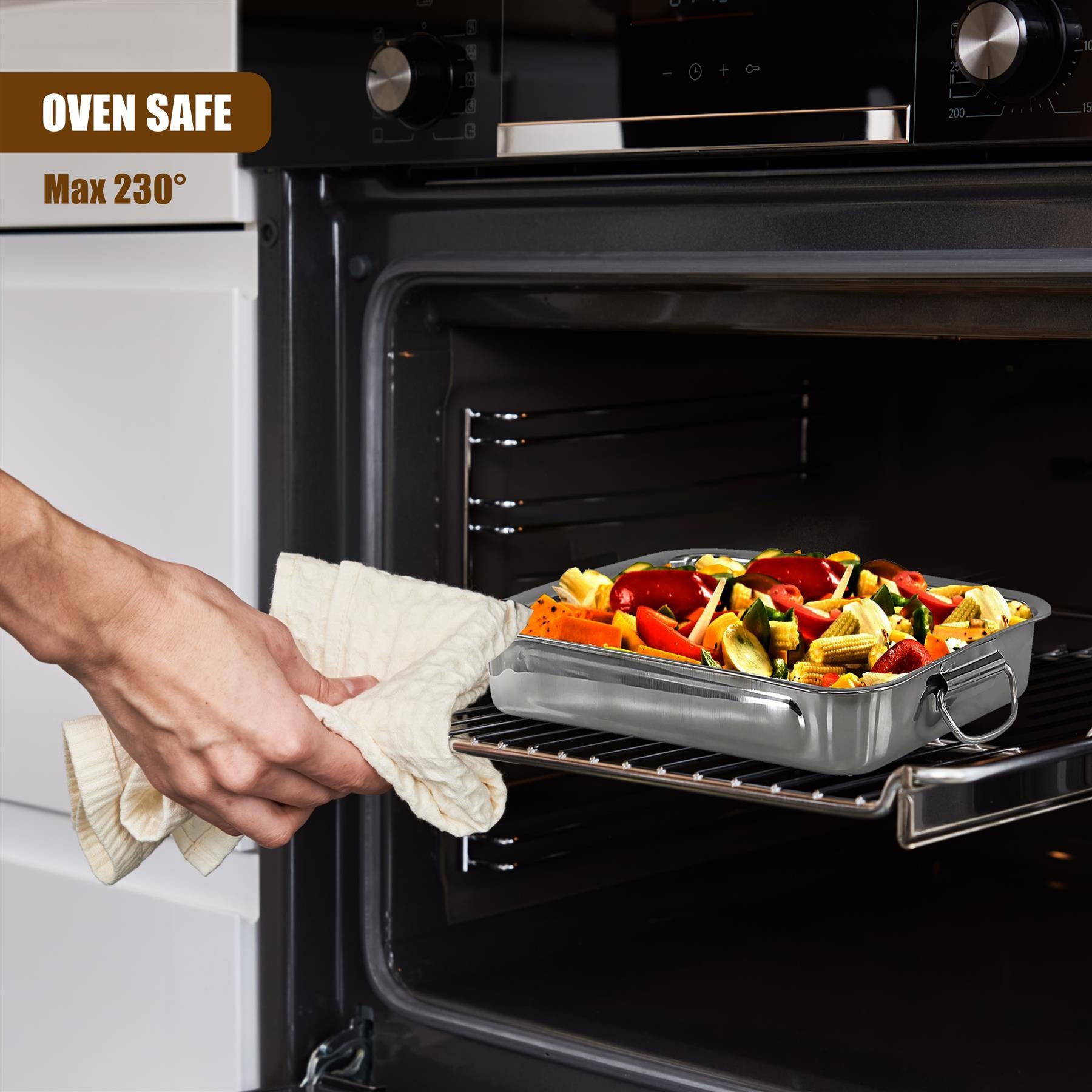 A hand using a cloth pulls a metal roasting tray filled with vegetables from inside the oven.