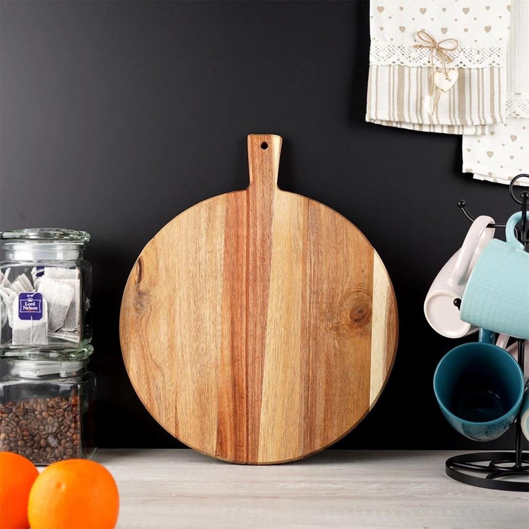 A wooden round cutting board with a handle on top, surrounded by a stack of tea bags, a jar of coffee beans, a fruit stand with oranges, and a mug stand with cups. - The Magic Toy Shop