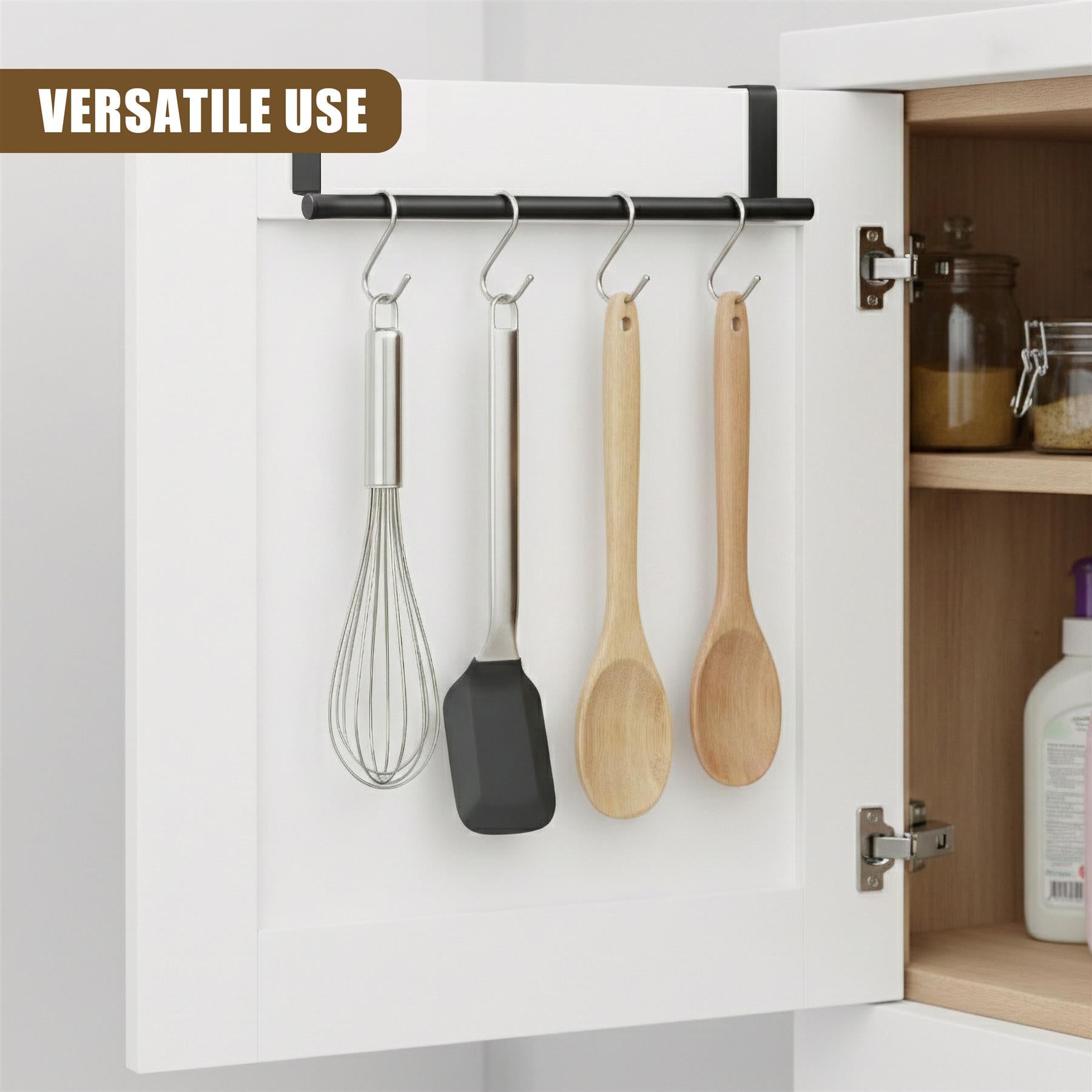 Black hanging rail inside a white cabinet holds a whisk, spatula, and two wooden spoons.
