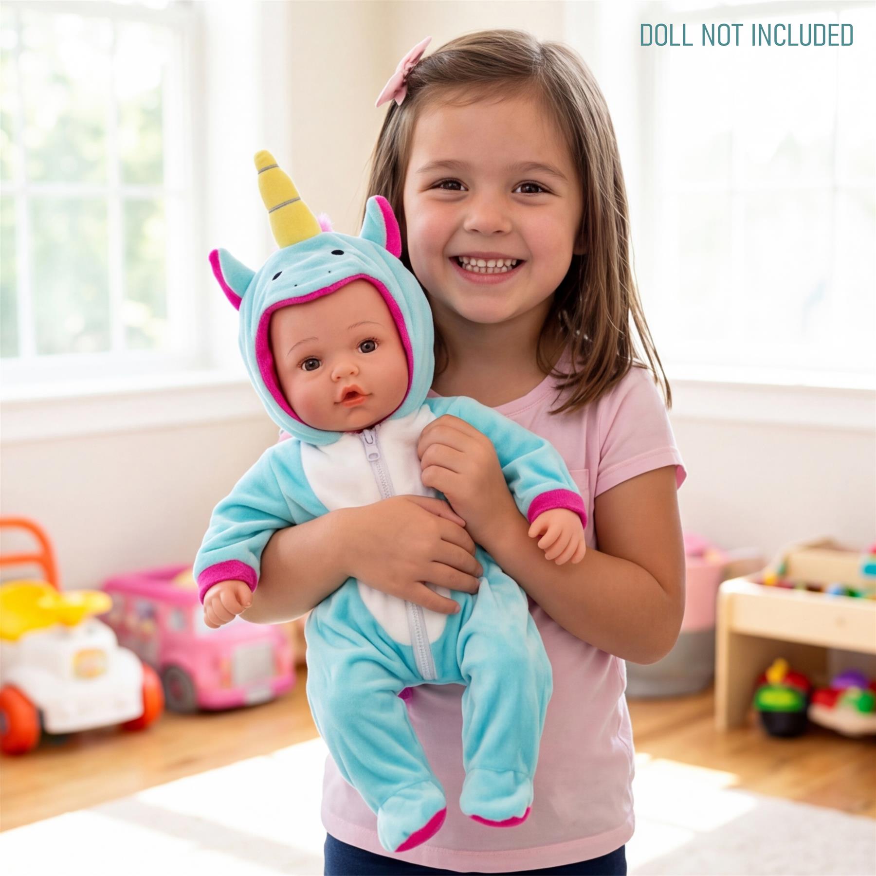 A smiling girl holds a doll wearing a light blue unicorn hooded outfit.