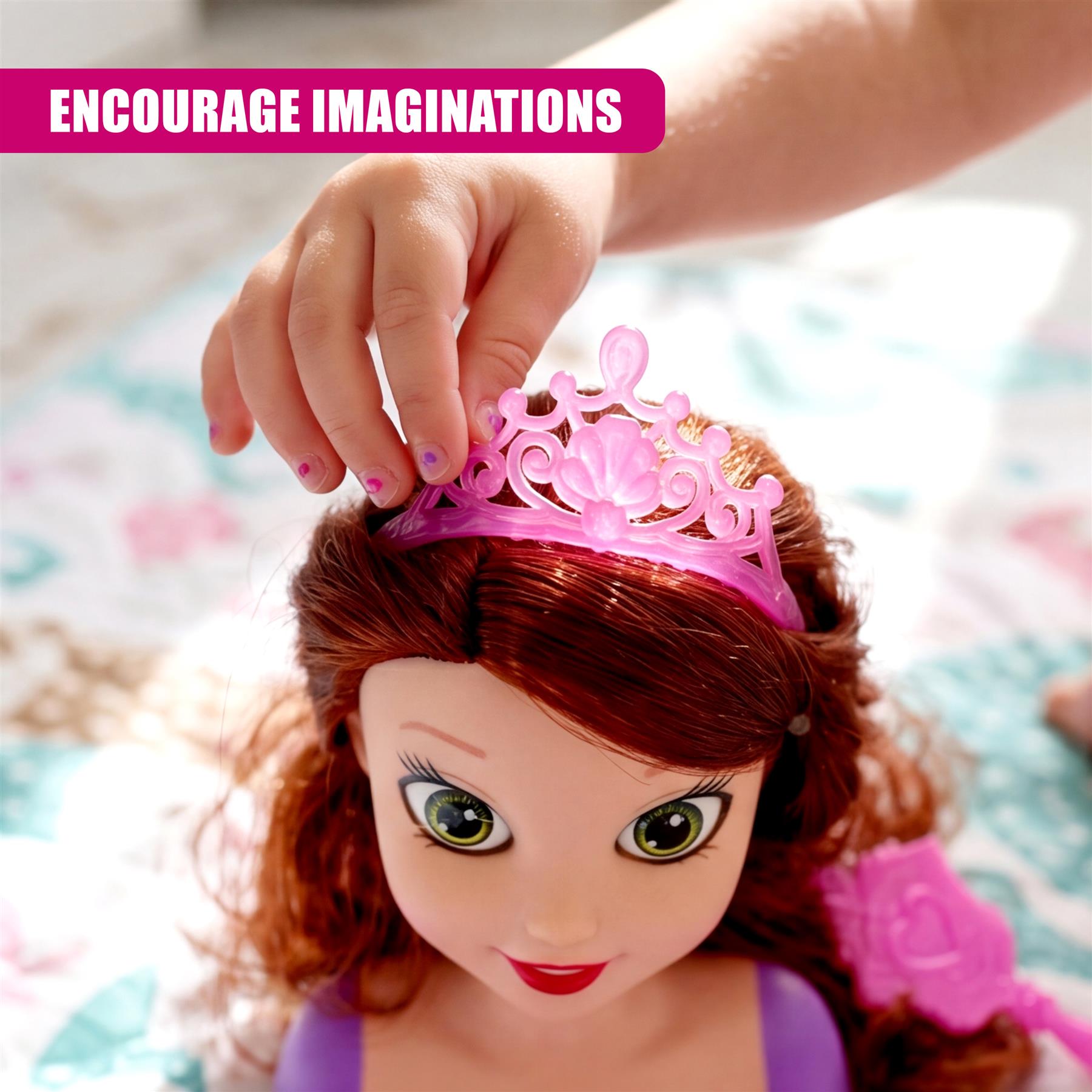 Hand placing a sparkly pink tiara crown onto the doll's red hair.