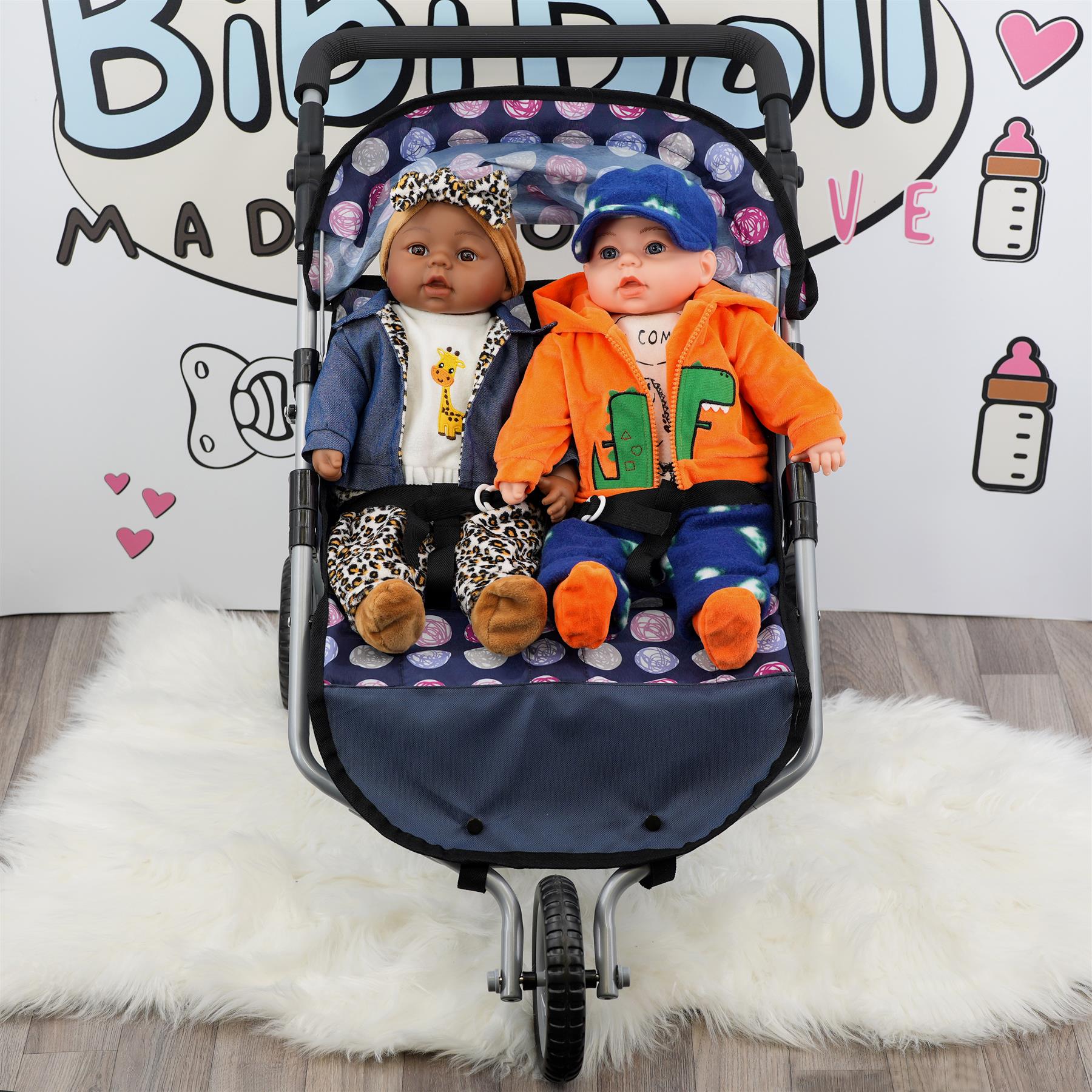 Blue twin pushchair holding two dolls wearing coordinated outfits and seated side-by-side.