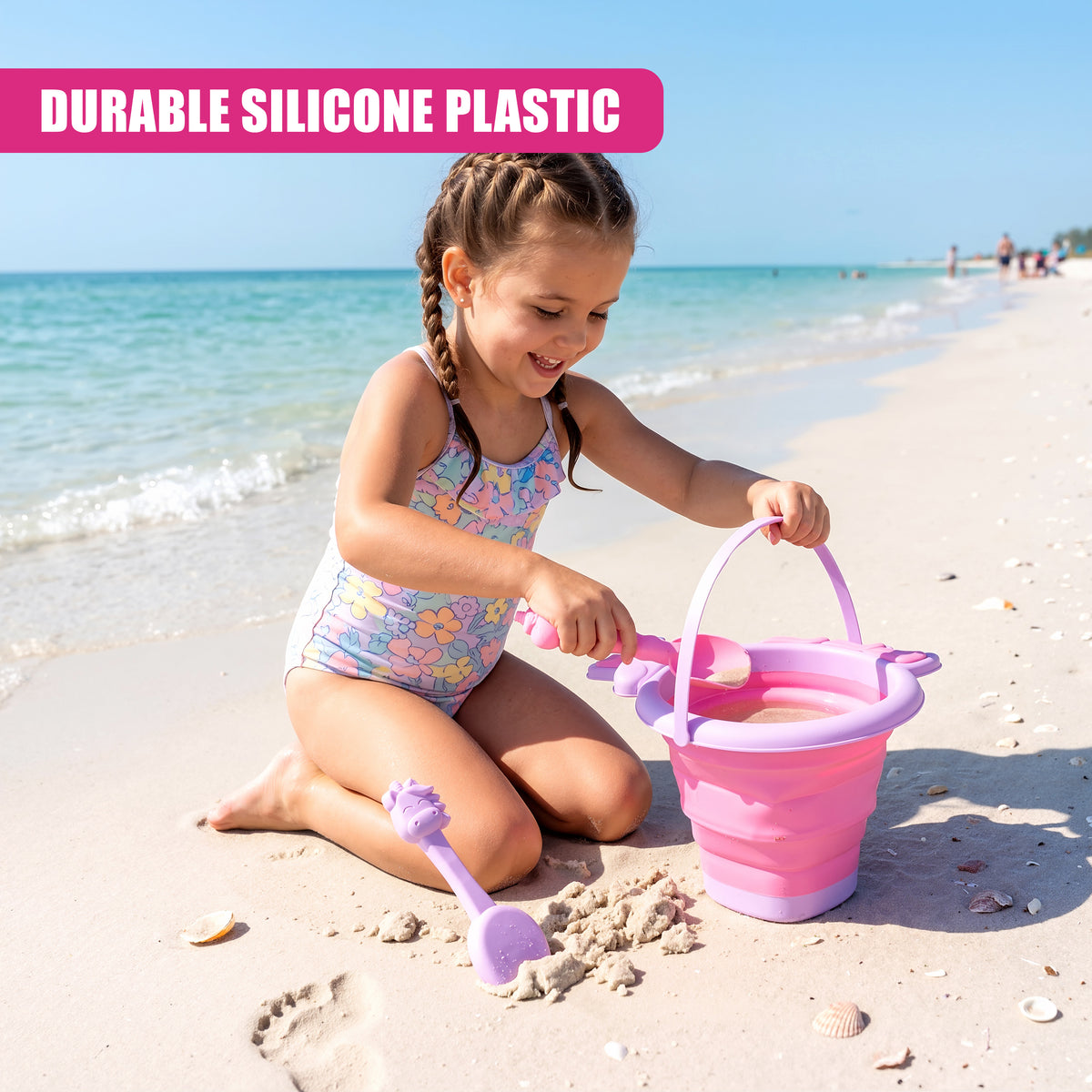 A young girl plays on a beach with a pink collapsible bucket and spade set
