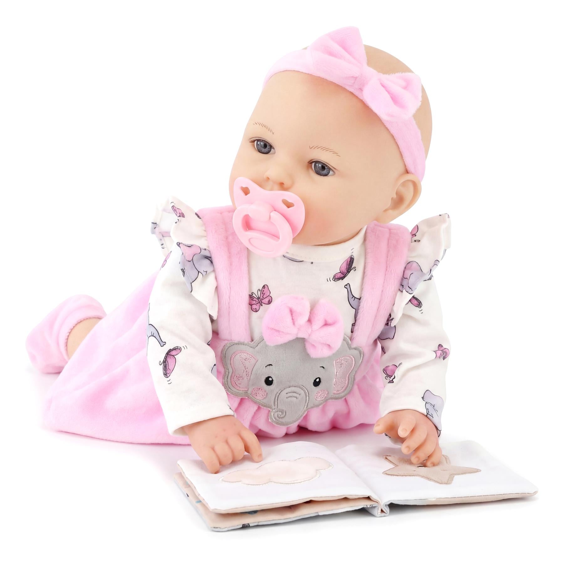 Doll sitting with an open book, wearing pink clothes, a headband, and a pacifier.