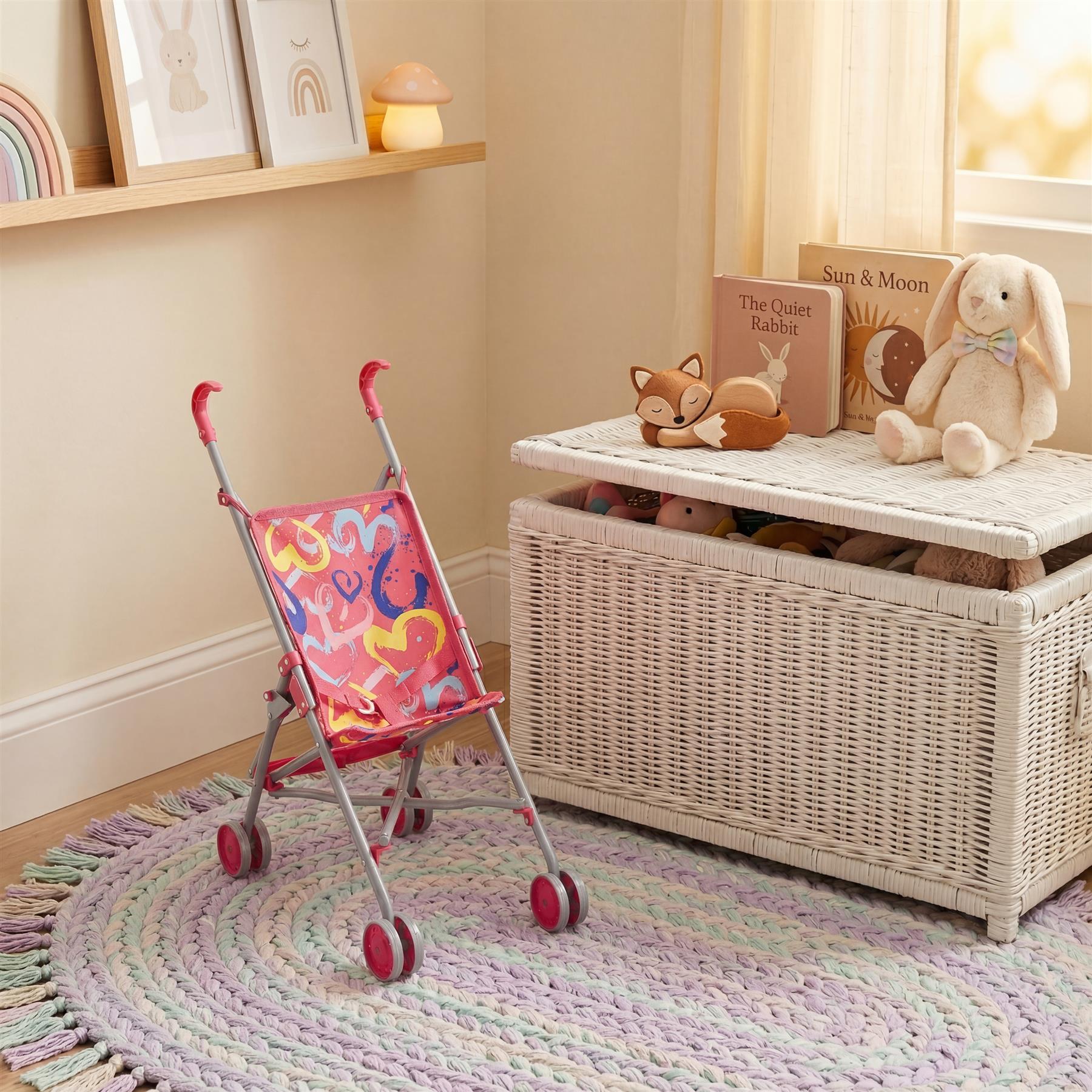 Pink doll's buggy stroller with red wheels sits on a lilac and cream knitted rug.