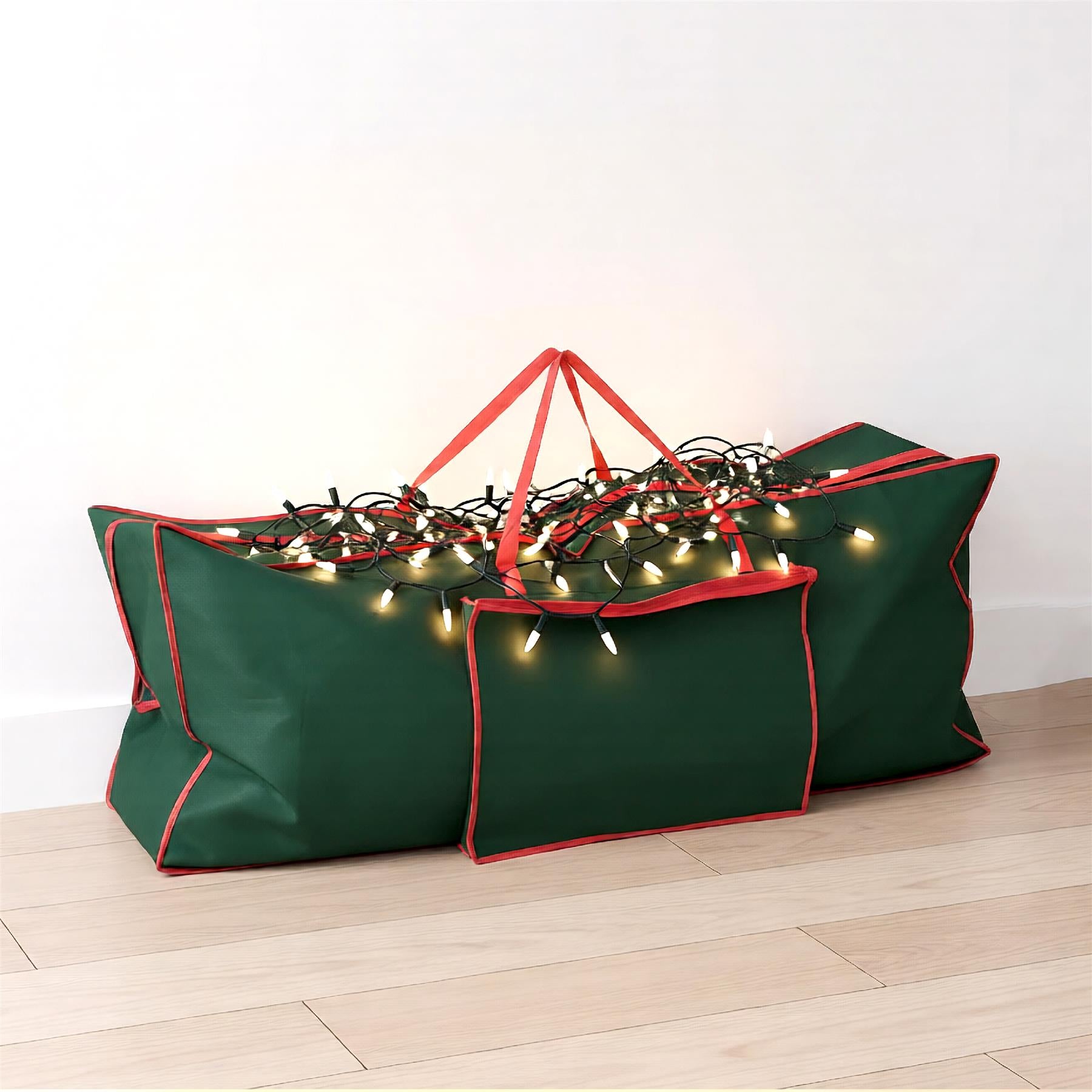 A green storage bag with red trim, filled with Christmas lights, sitting on a light wood floor. - The Magic Toy Shop