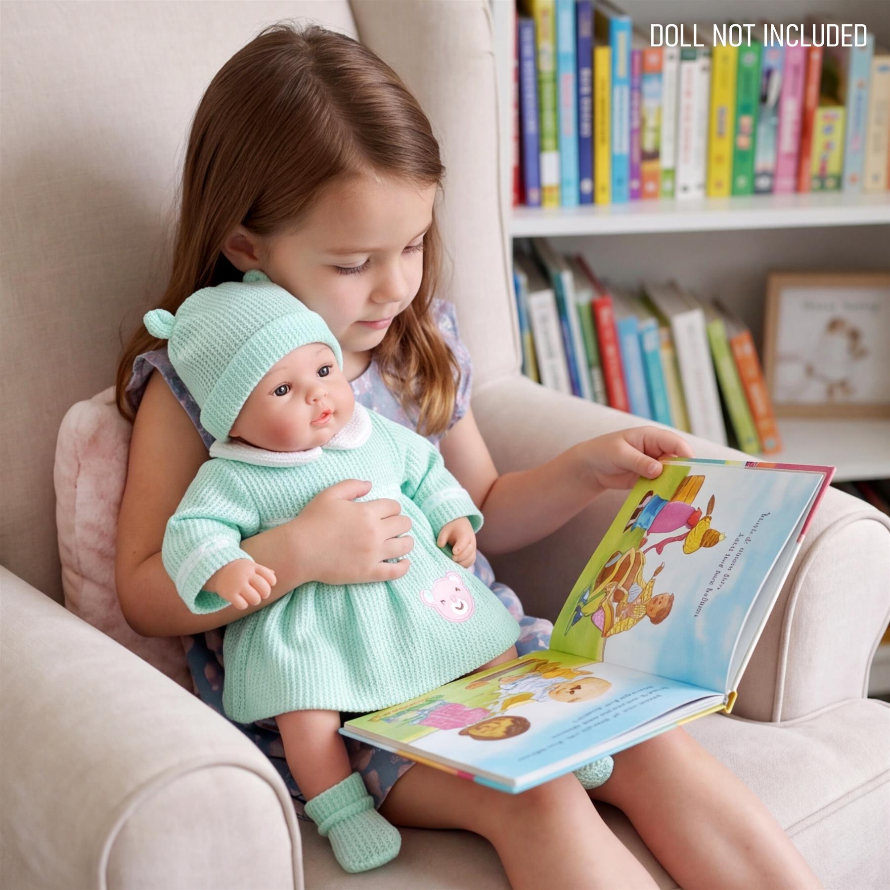A doll in a mint green outfit is held by a girl viewing a colorful picture book.