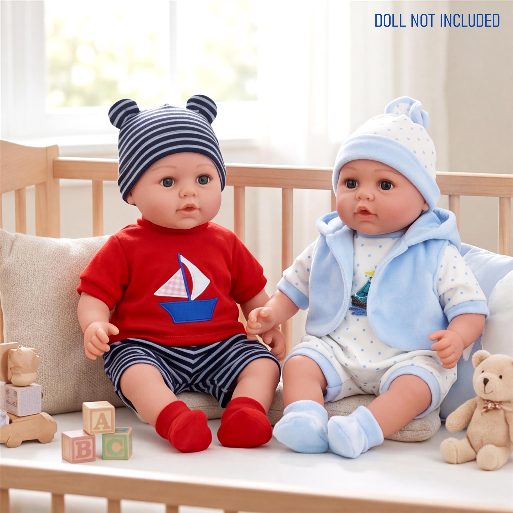 Two dolls sit in a crib, modeling contrasting red and blue and light blue outfits.