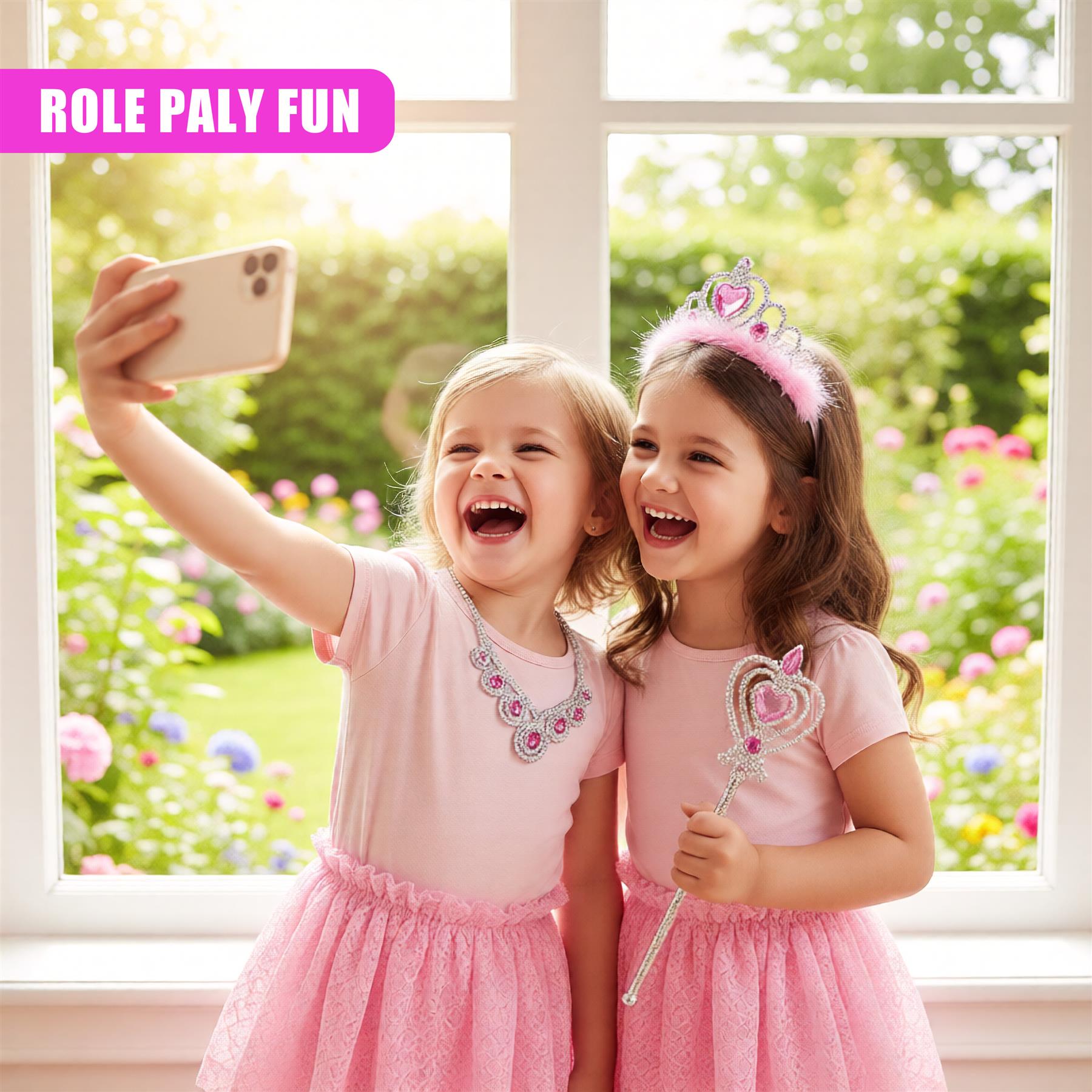 Two young girls, dressed in pink, take a selfie together, smiling and laughing. One girl holds a sparkly wand and wears a tiara. The background is a bright, sunny garden with colorful flowers and lush greenery. - The Magic Toy Shop
