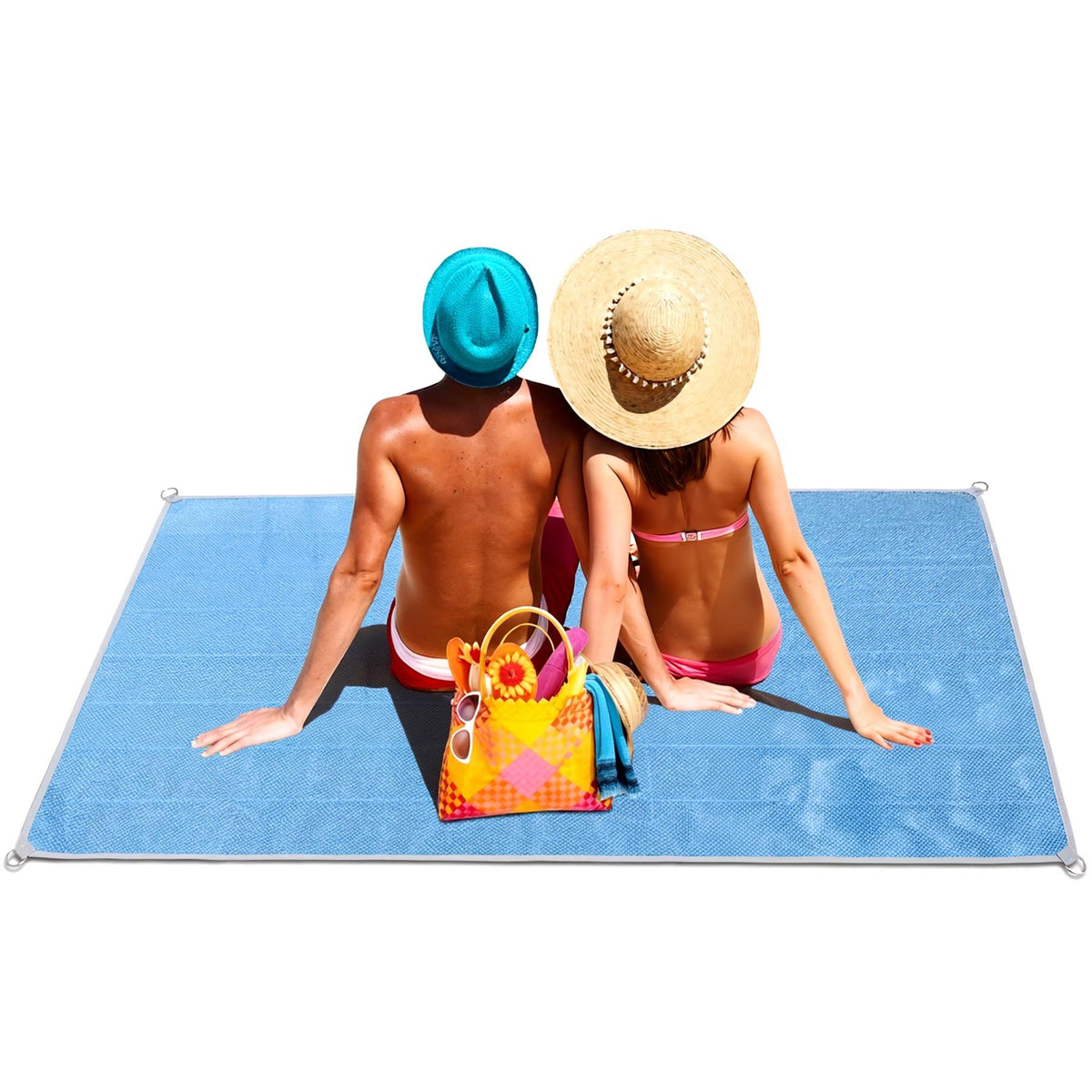 A couple sits on a blue GEEZY sand-free beach mat, wearing hats and sunglasses