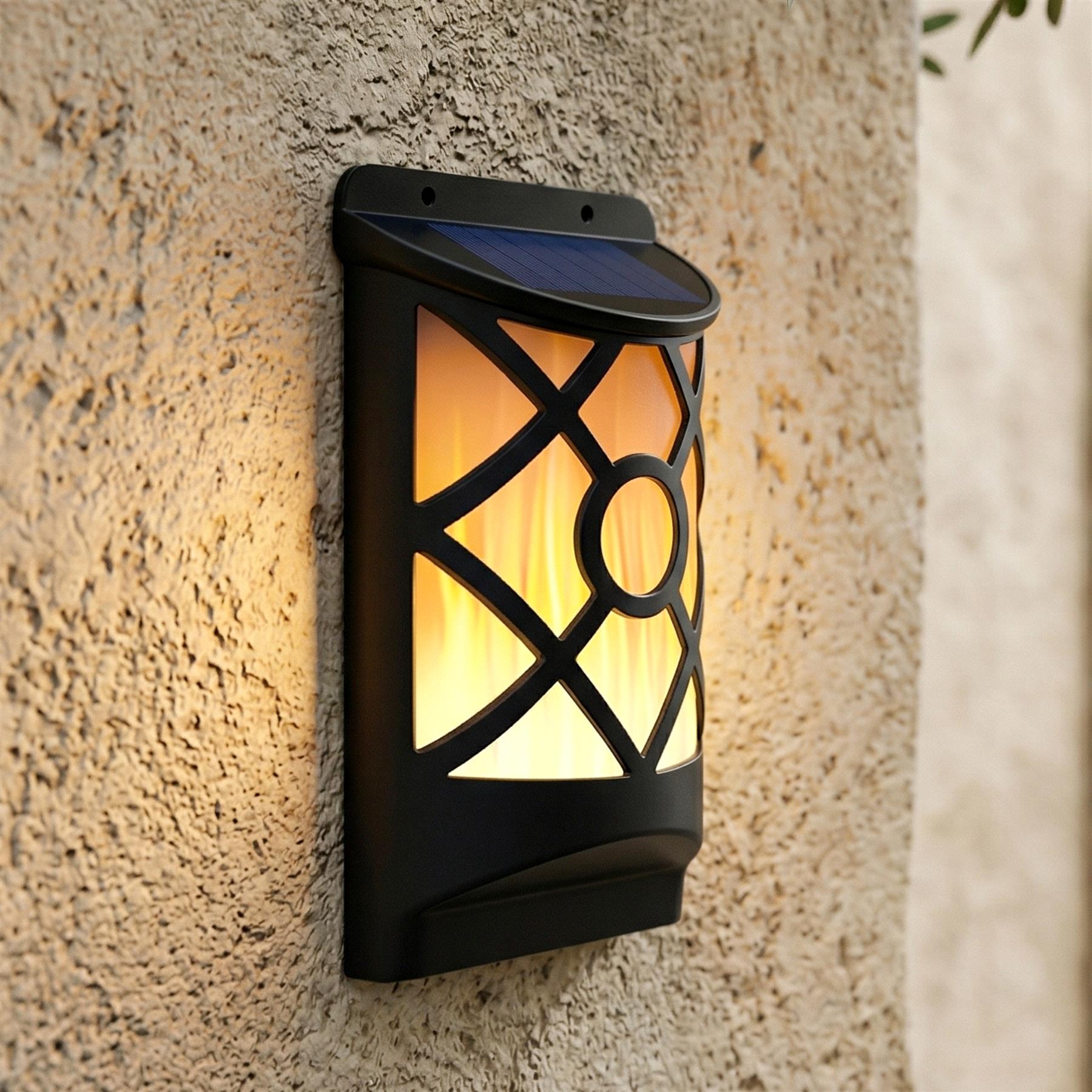 Black lantern-style solar light fixture mounted on a textured wall, casting warm light through a decorative pattern.