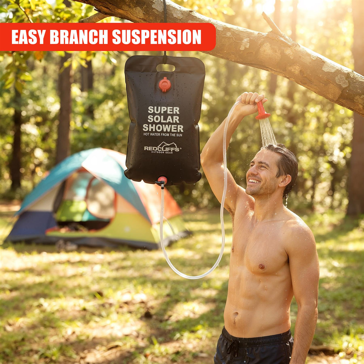 A man enjoys a hot shower from a GEEZY Solar Shower Bag hanging from a tree branch
