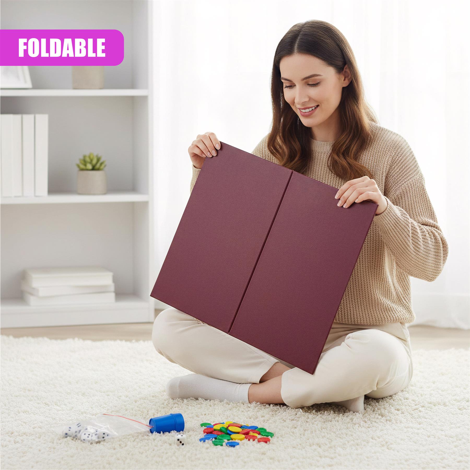 Woman sitting on a floor holding a foldable game board and several playing pieces and dice.