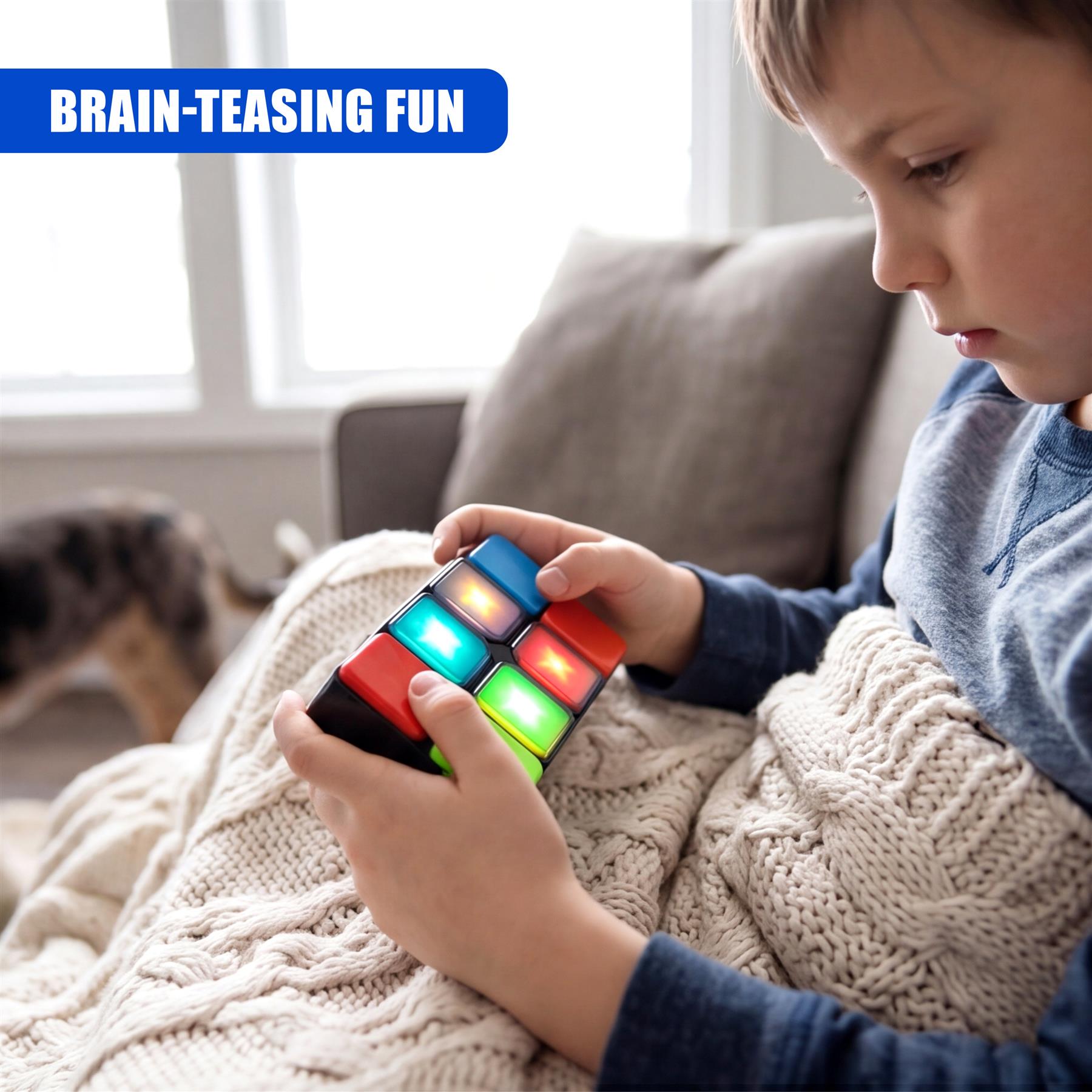 A boy holds a multicolored, handheld cube game while sitting under a white knit blanket.